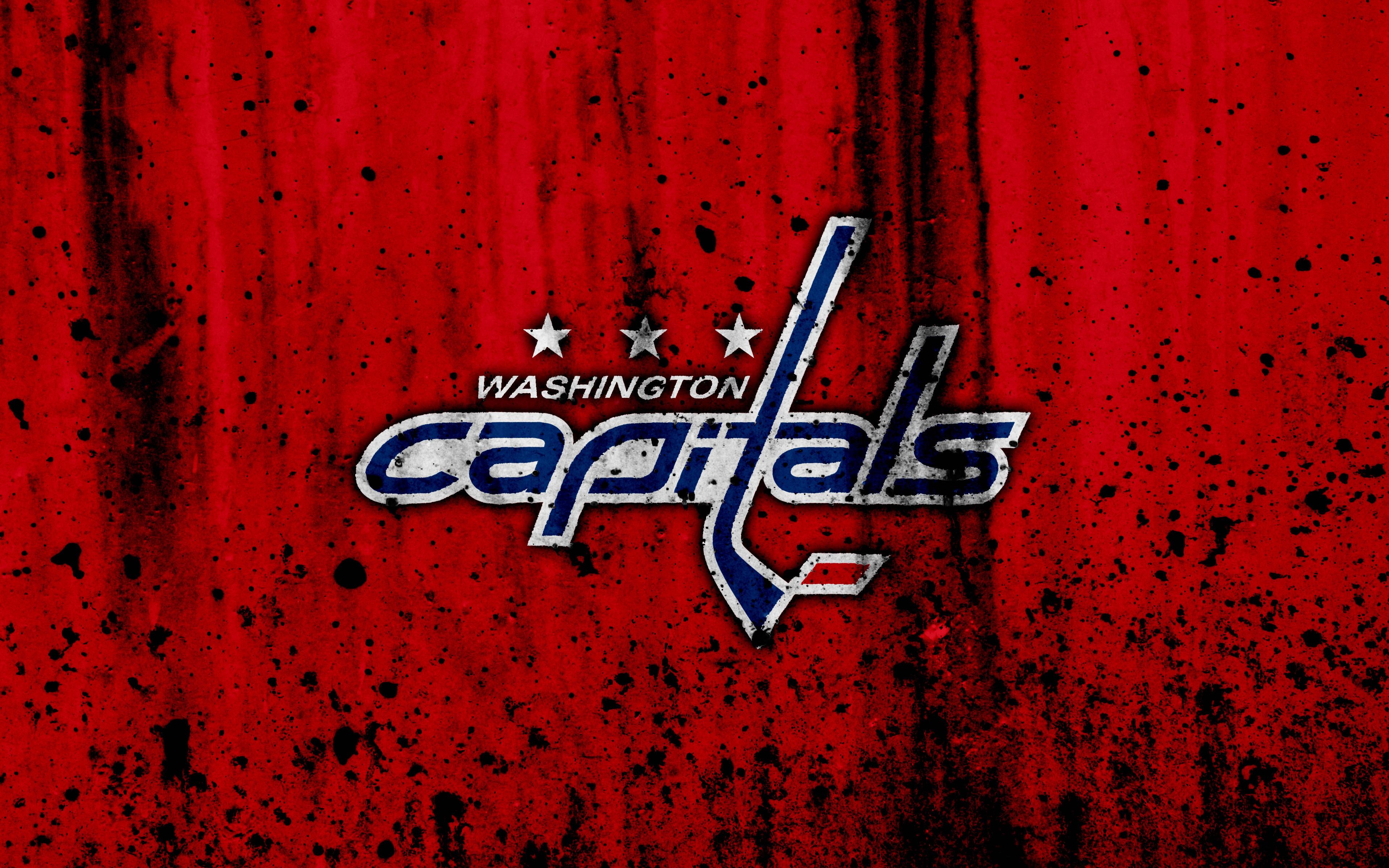 Washington Capitals 桌布 壁紙 — 華盛頓首都隊標誌，以粗體藍色和銀色呈現，置於帶有黑色潑濺效果的紋理紅色背景上。