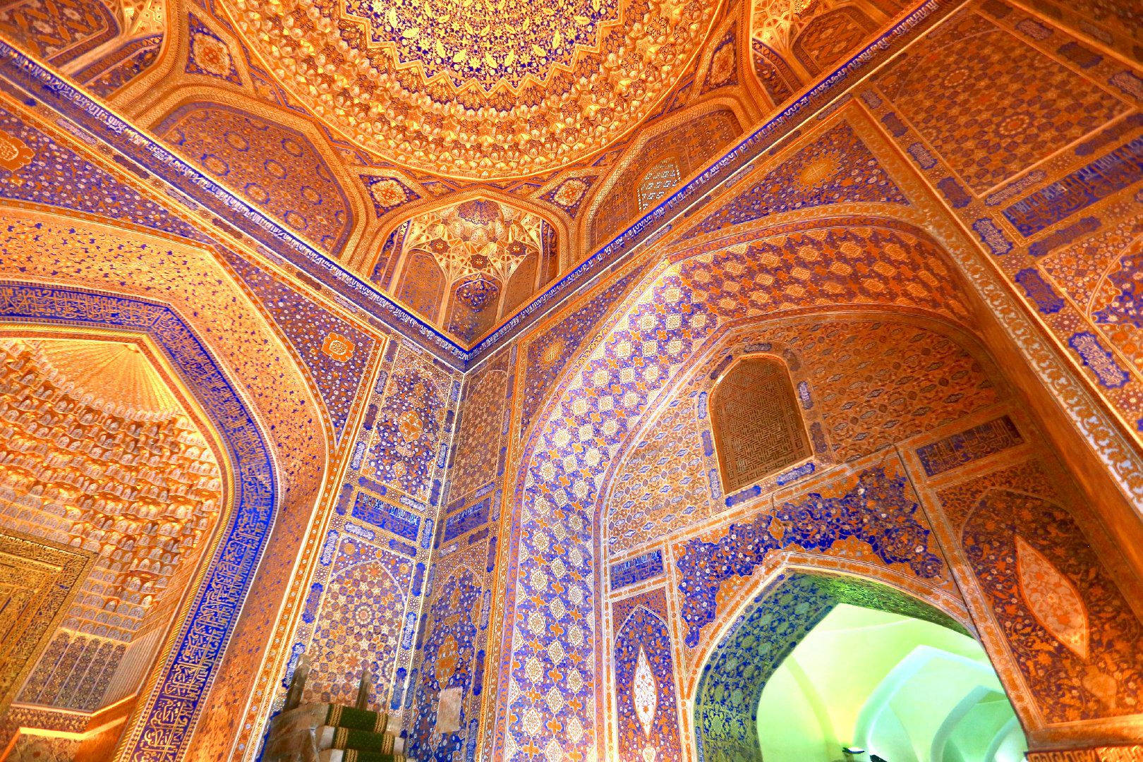 Uzbekistan 桌布 壁紙 — 華麗的伊斯蘭建築內部向上看的驚人景色，精緻的藍色和金色瓷磚覆蓋著圓頂天花板和拱形牆壁。