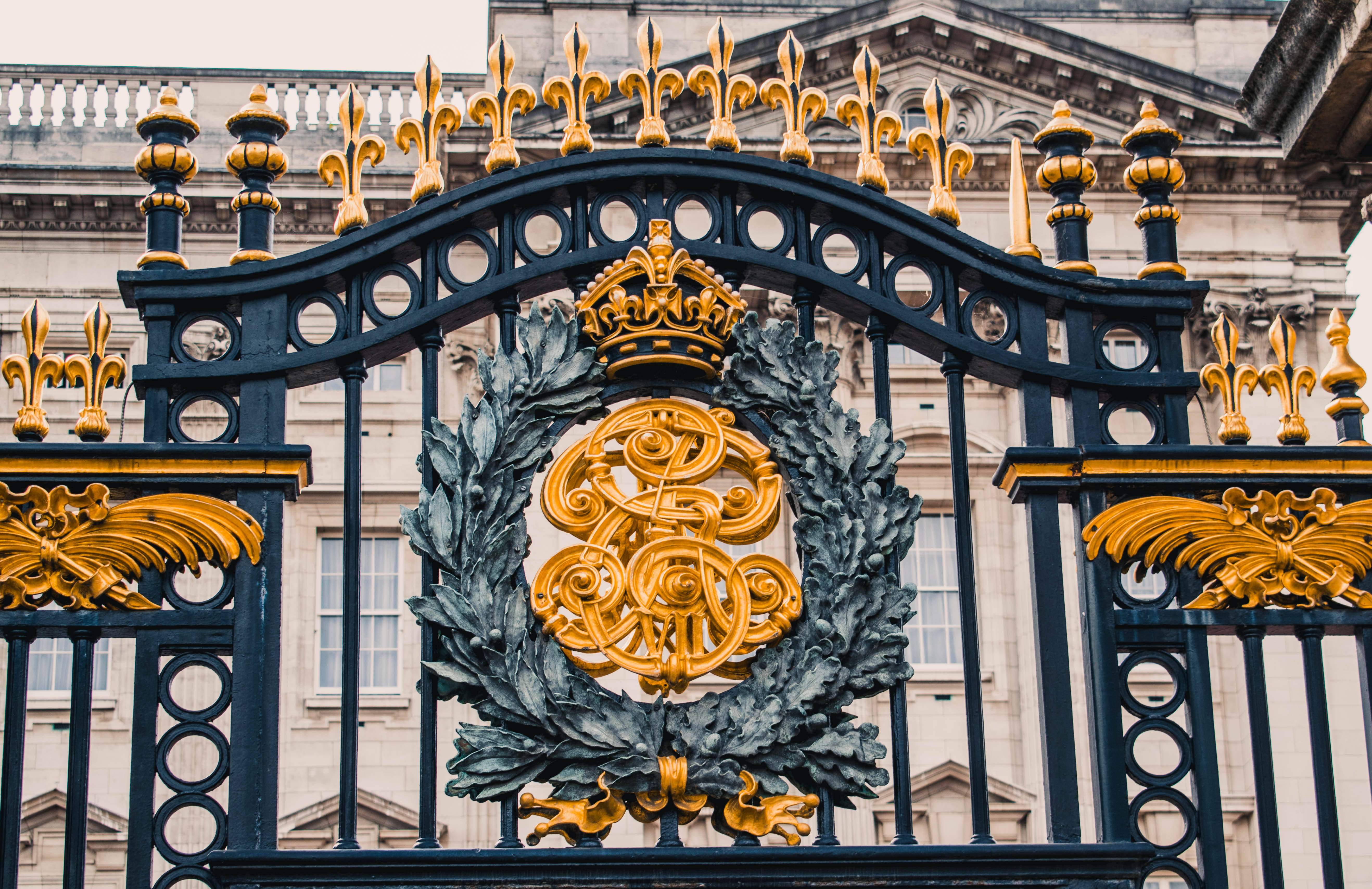 England 桌布 壁紙 — 華麗的黑金皇家大門特寫，帶有皇冠和月桂花環標誌，背景是莊嚴的石建築。