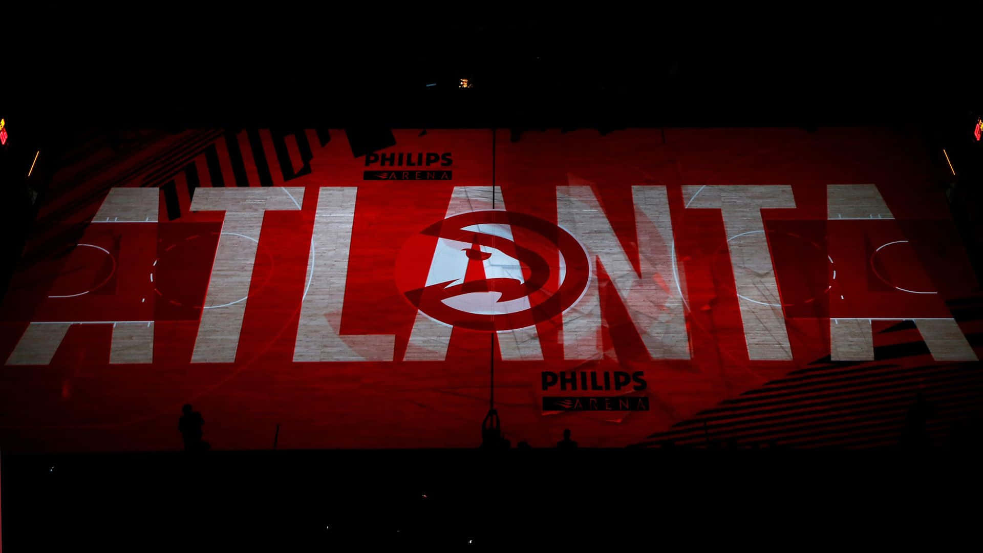 Atlanta Hawks 桌布 壁紙 — 菲利普斯體育館的籃球場被紅光籠罩，'ATLANTA' 和老鷹隊標誌以粗體白色字母投影。