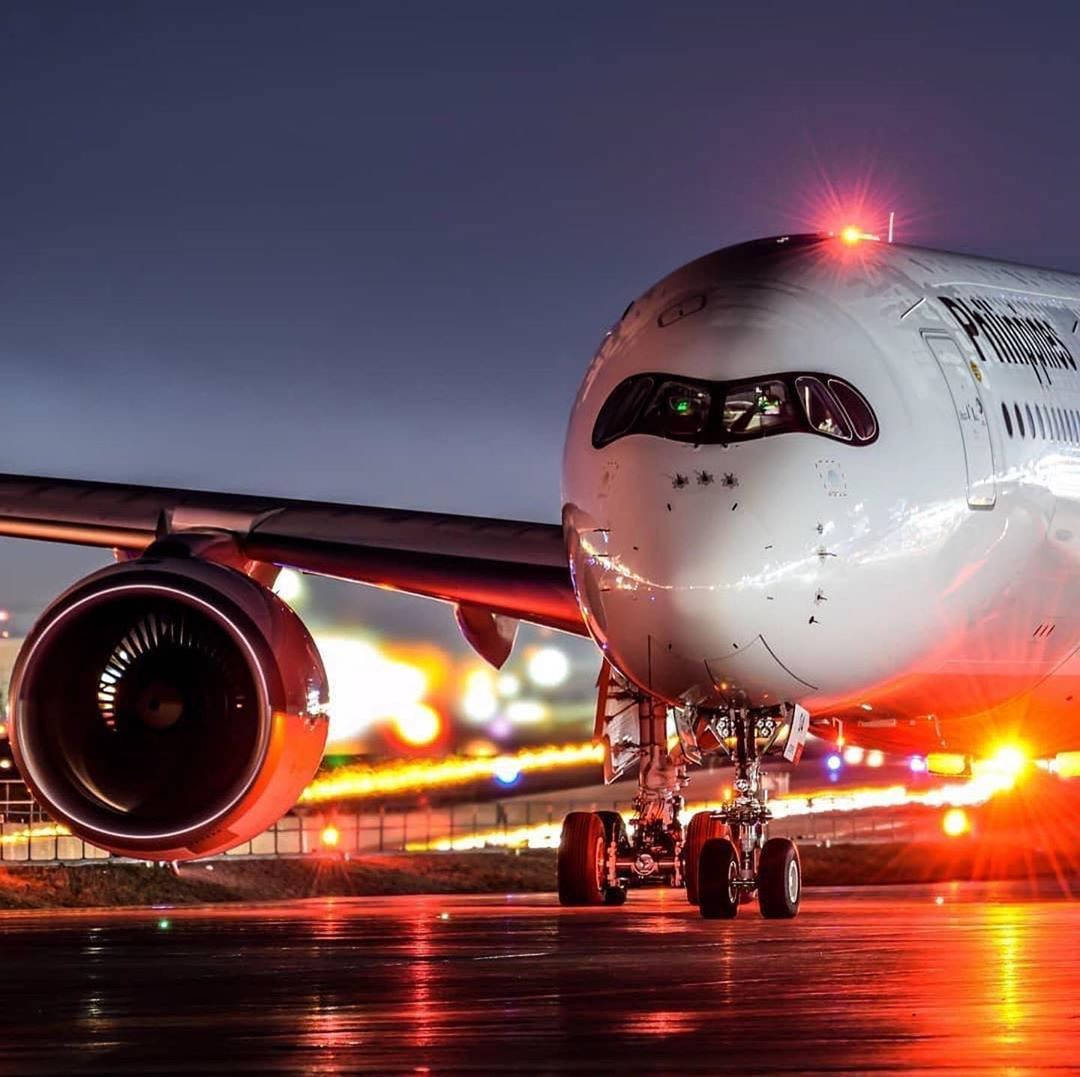 Airport 桌布 壁紙 — 菲律賓航空噴射客機在夜間潮濕的停機坪上，在鮮紅色的跑道燈光下閃閃發光。
