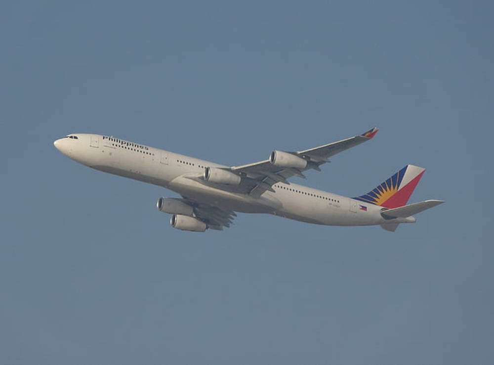 飛機 桌布 壁紙 — 菲律賓航空的空中巴士A340在清澈的藍天中優雅翱翔，帶有其獨特的太陽光線尾翼設計。