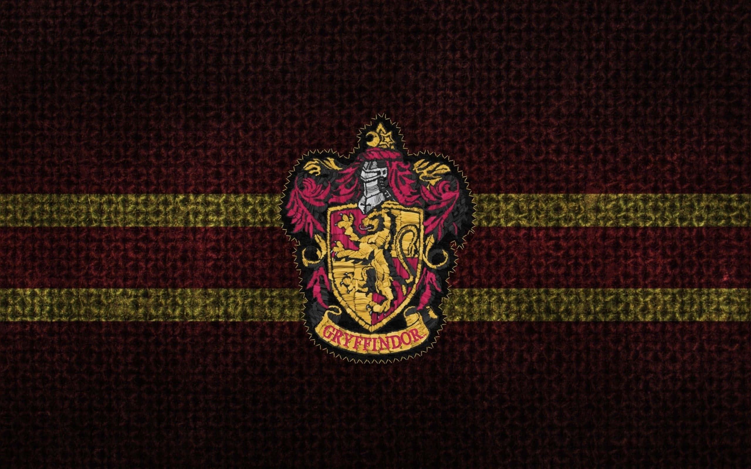 Harry Potter Gryffindor 桌布 壁紙 — 葛萊芬多學院徽章置於帶有金色條紋的質感栗色布料中央。