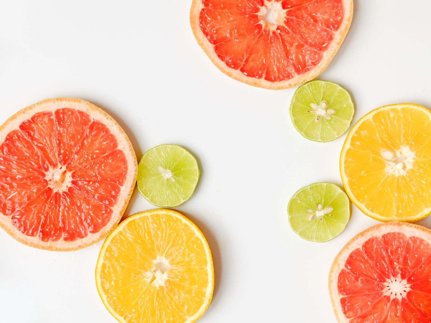 Fruit 桌布 壁紙 — 葡萄柚、萊姆和柳橙的鮮豔橫切面排列在潔白的表面上。