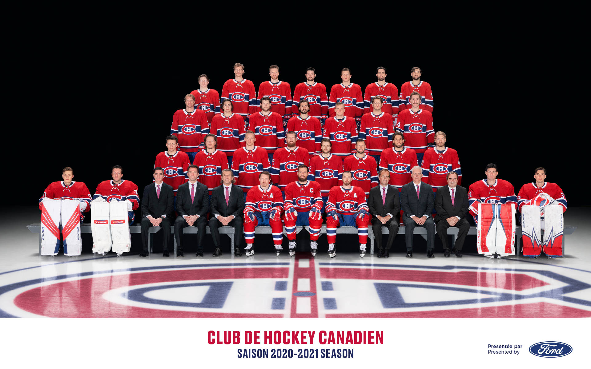 Canadiens 桌布 壁紙 — 蒙特婁加拿大人冰球隊在明亮的攝影棚燈光下，穿著紅色球衣在冰場上擺姿勢，並展示球隊標誌。