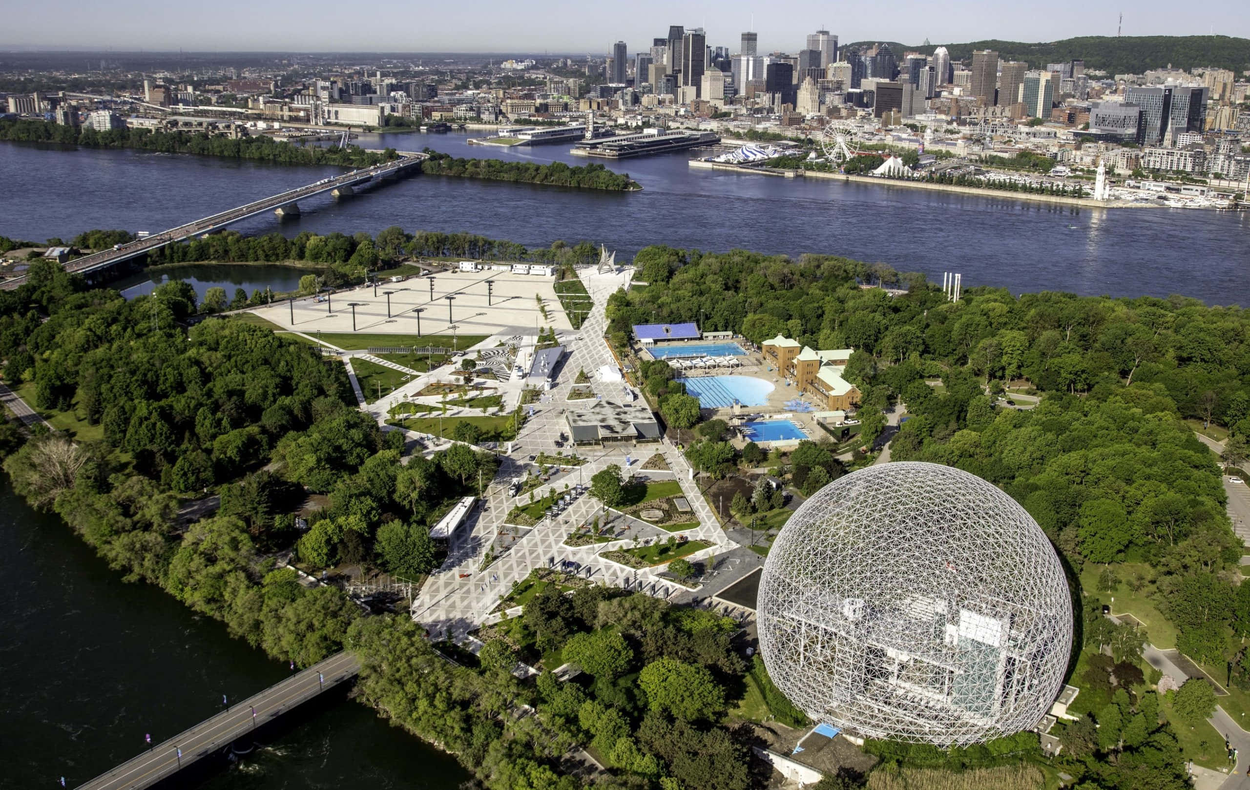 Biosphere 桌布 壁紙 — 蒙特婁生物圈及周邊公園的鳥瞰圖，背景為城市天際線和河流。