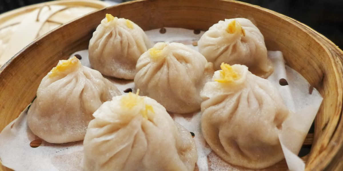 Chinese Food 桌布 壁紙 — 蒸餃子金黃色的內餡放在鋪有烘焙紙的竹蒸籠中。