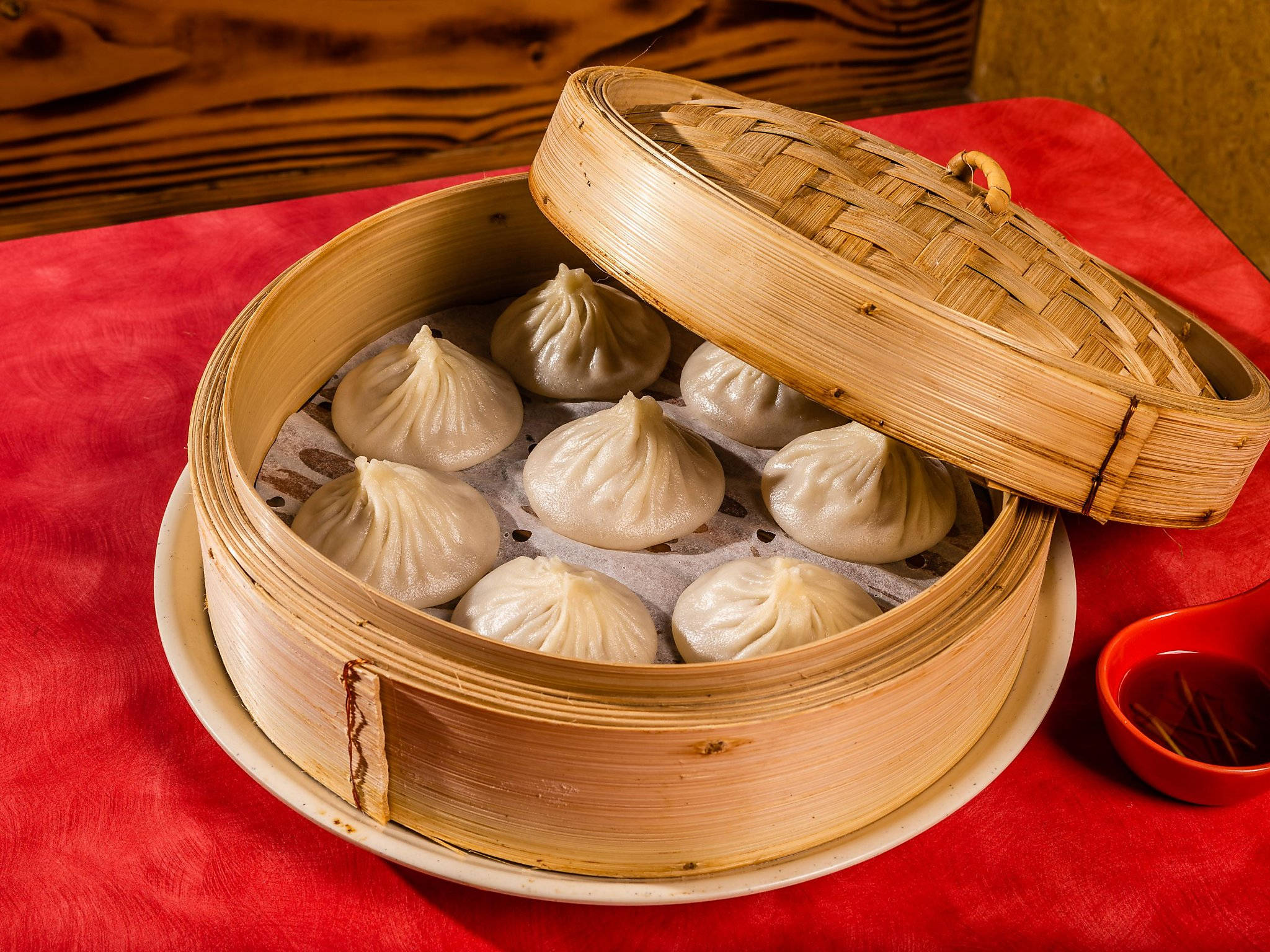 steam 桌布 壁紙 — 蒸餃放在竹蒸籠裡，置於鮮紅色桌布上，附有蘸醬。