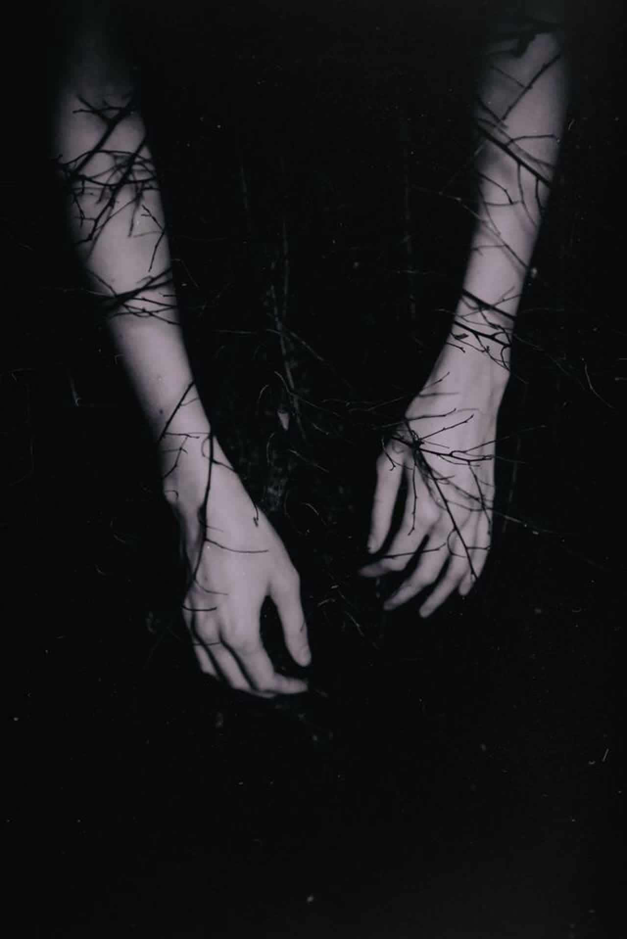 Aesthetic Black 桌布 壁紙 — 蒼白的手從黑暗中浮現，纏繞著光禿禿的樹枝，構成一個令人不安的黑白構圖。