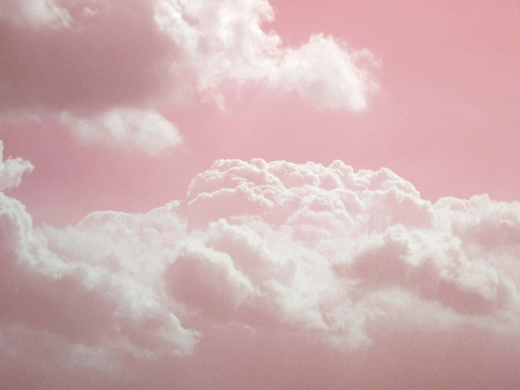 Pink And White Aesthetic 桌布 壁紙 — 蓬鬆的白雲在柔和的粉紅色天空中飄移，形成夢幻的粉彩漸變。