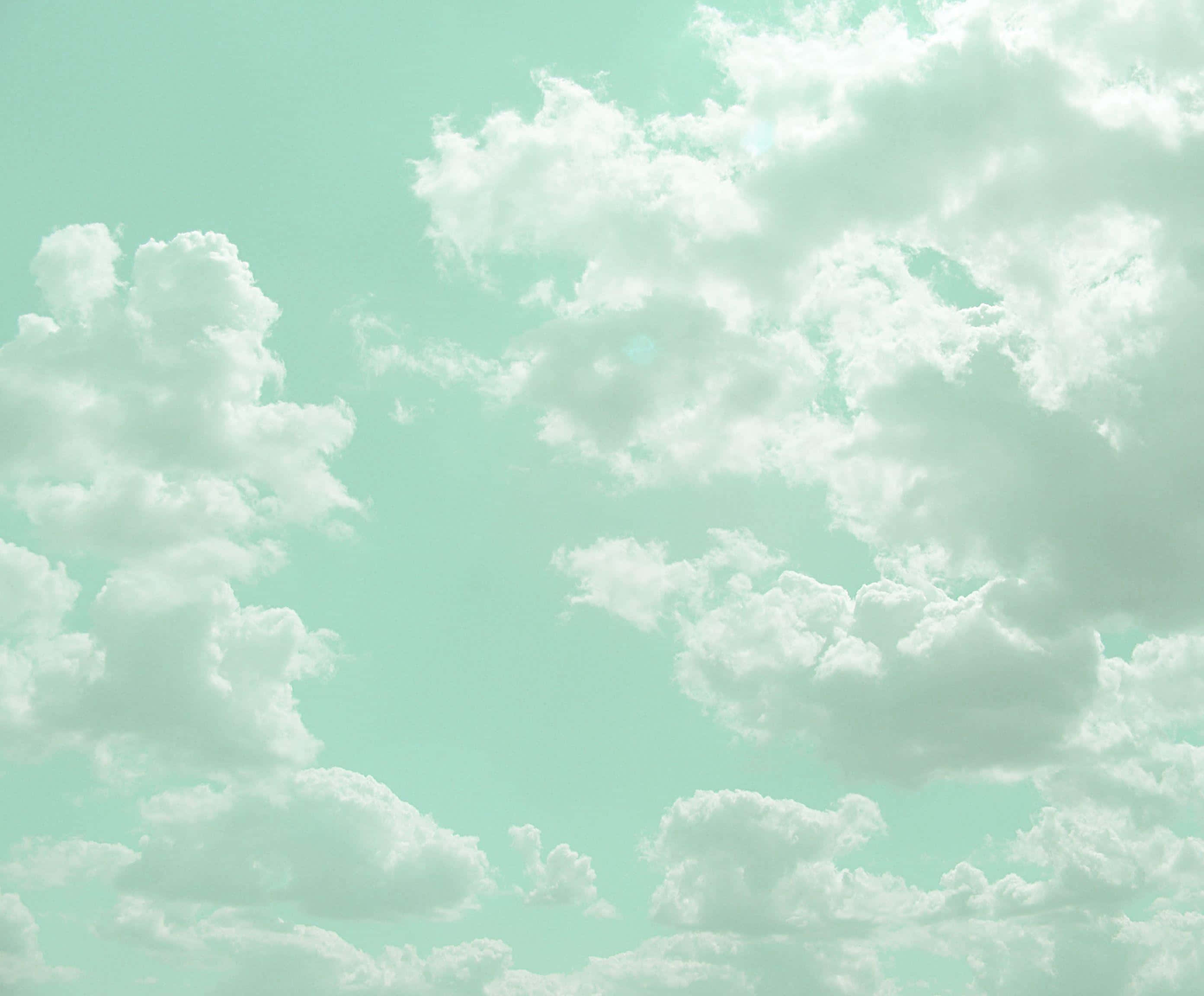 Aesthetic Cloud 桌布 壁紙 — 蓬鬆的白雲在柔和的薄荷綠天空中飄移，營造出寧靜夢幻的氛圍。