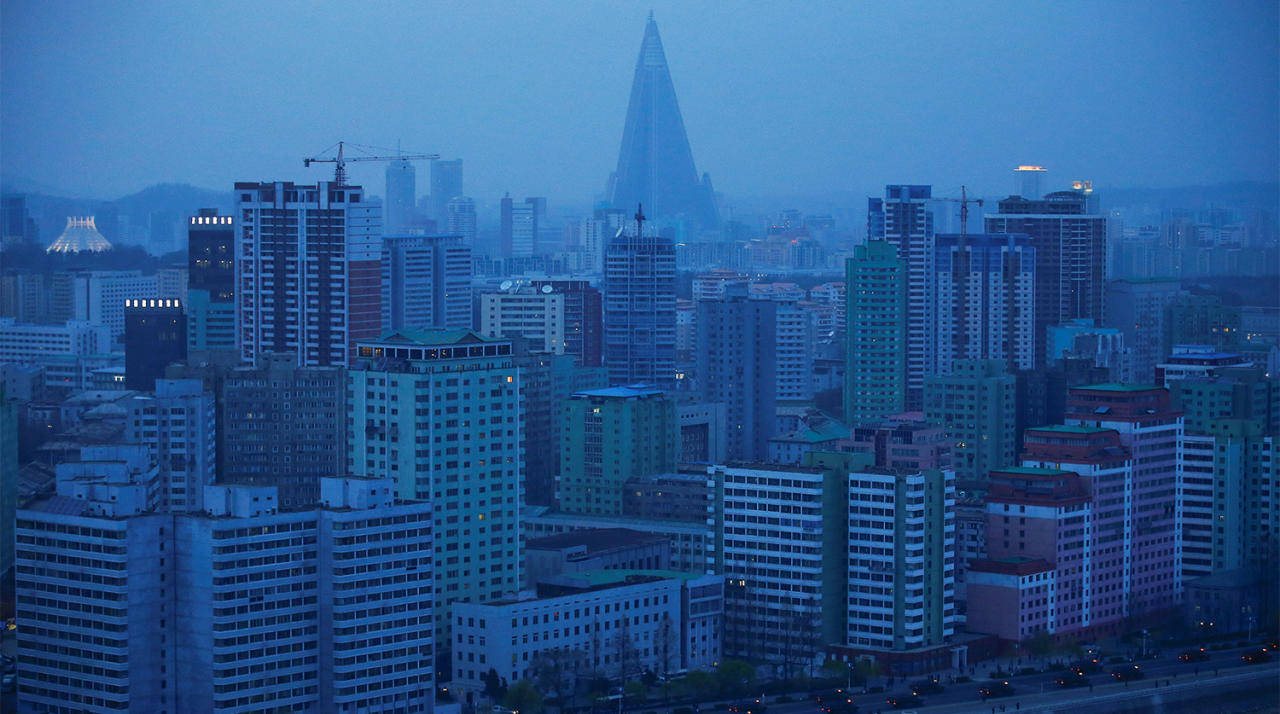 韓國 桌布 壁紙 — 薄霧籠罩的暮色城市景觀，高聳的建築物和一座突出的金字塔形摩天大樓刺穿朦朧的藍天。