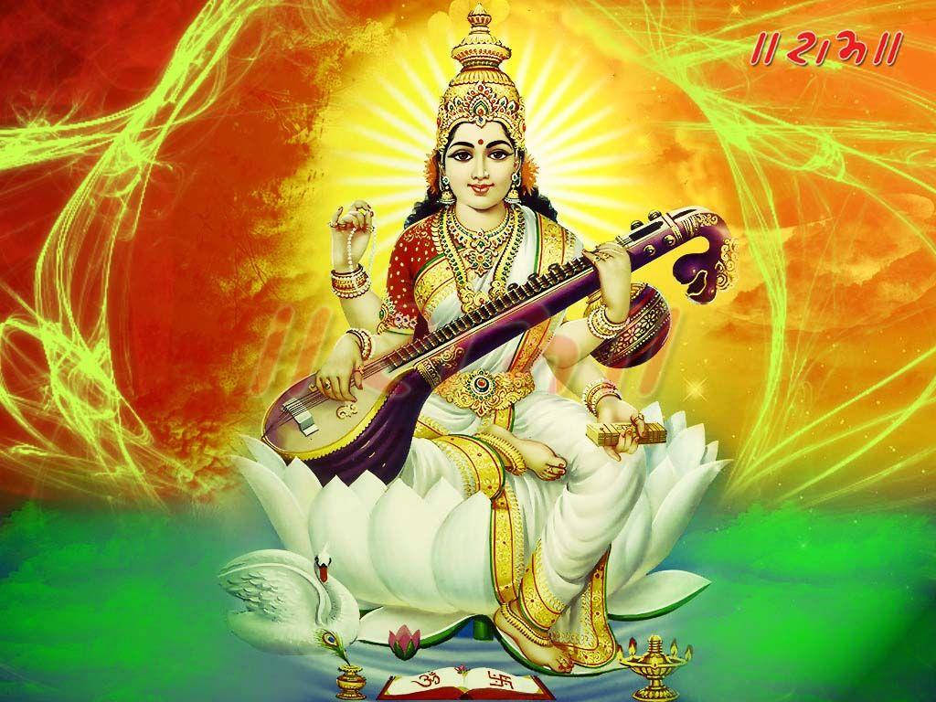 Saraswati Mata 桌布 壁紙 — 薩拉斯瓦蒂女神優雅地坐在白色蓮花上，手持維納琴，背景是光芒四射的橙色和綠色宇宙背景。