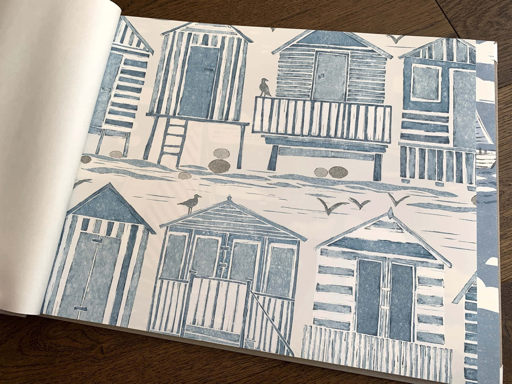 Beach Huts 桌布 壁紙 — 藍白插圖風格的海灘小屋壁紙圖案，小鳥在木質表面上空飛翔。