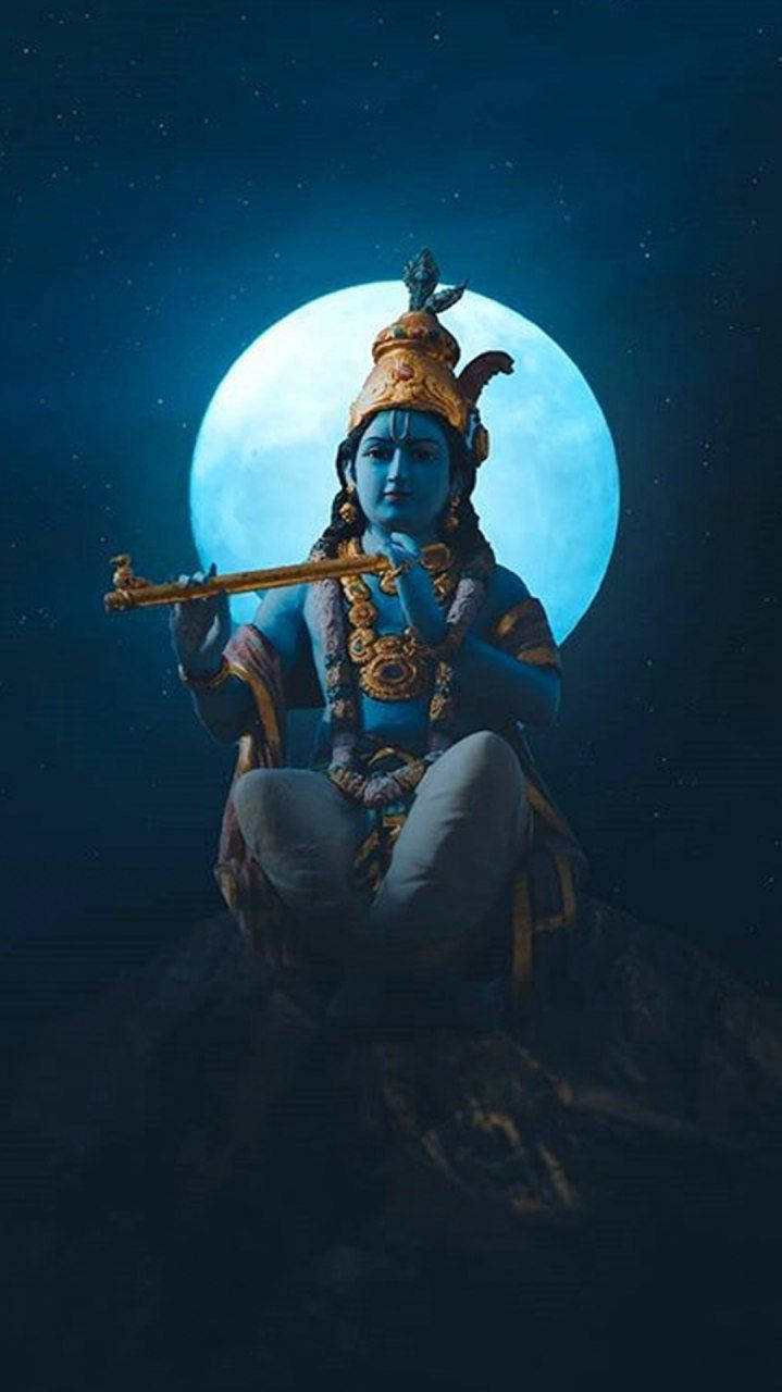 krishna iPhone 桌布 壁紙 — 藍皮膚的神祇克里希納盤腿坐在岩石上，對著明亮的滿月和繁星點點的夜空吹奏長笛。