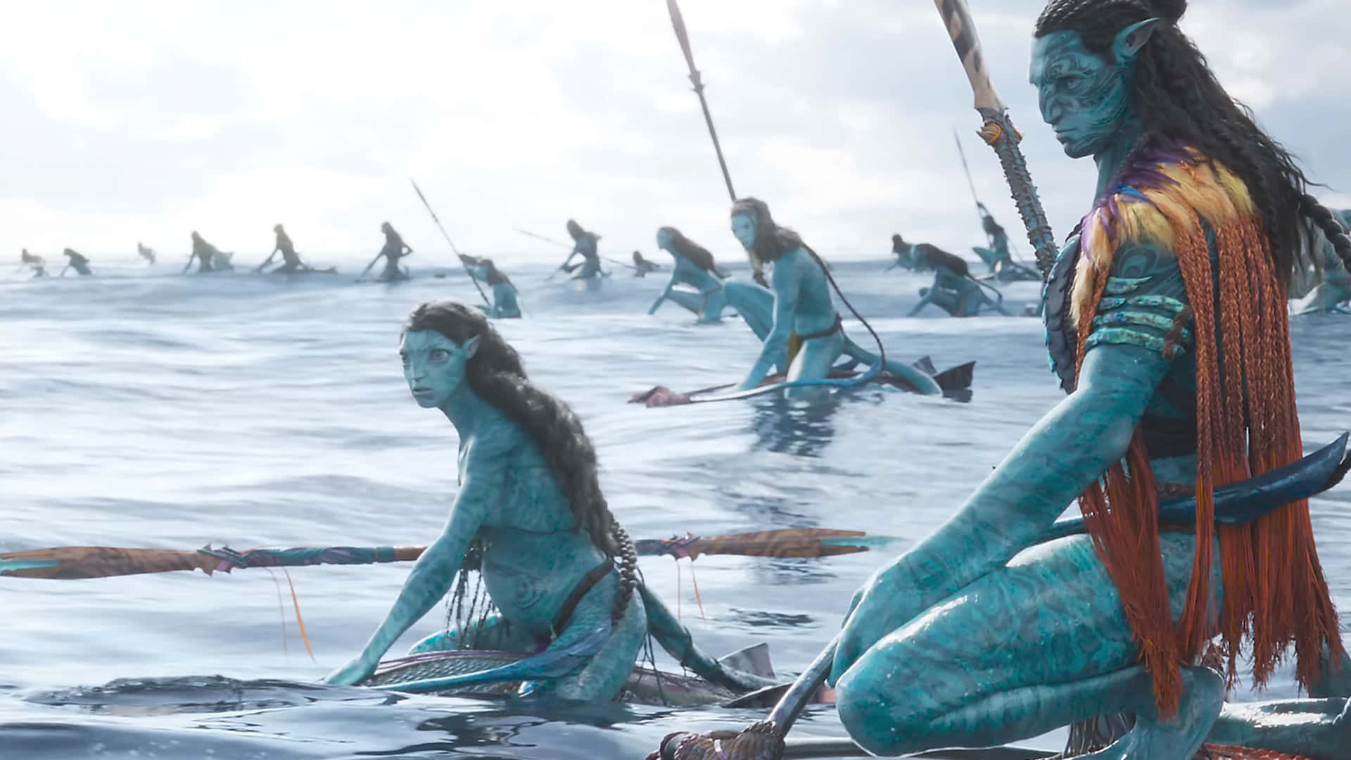 Avatar 2 The Way Of Water 桌布 壁紙 — 藍皮膚的納美戰士在明亮的天空下划著長船穿越平靜的海洋。