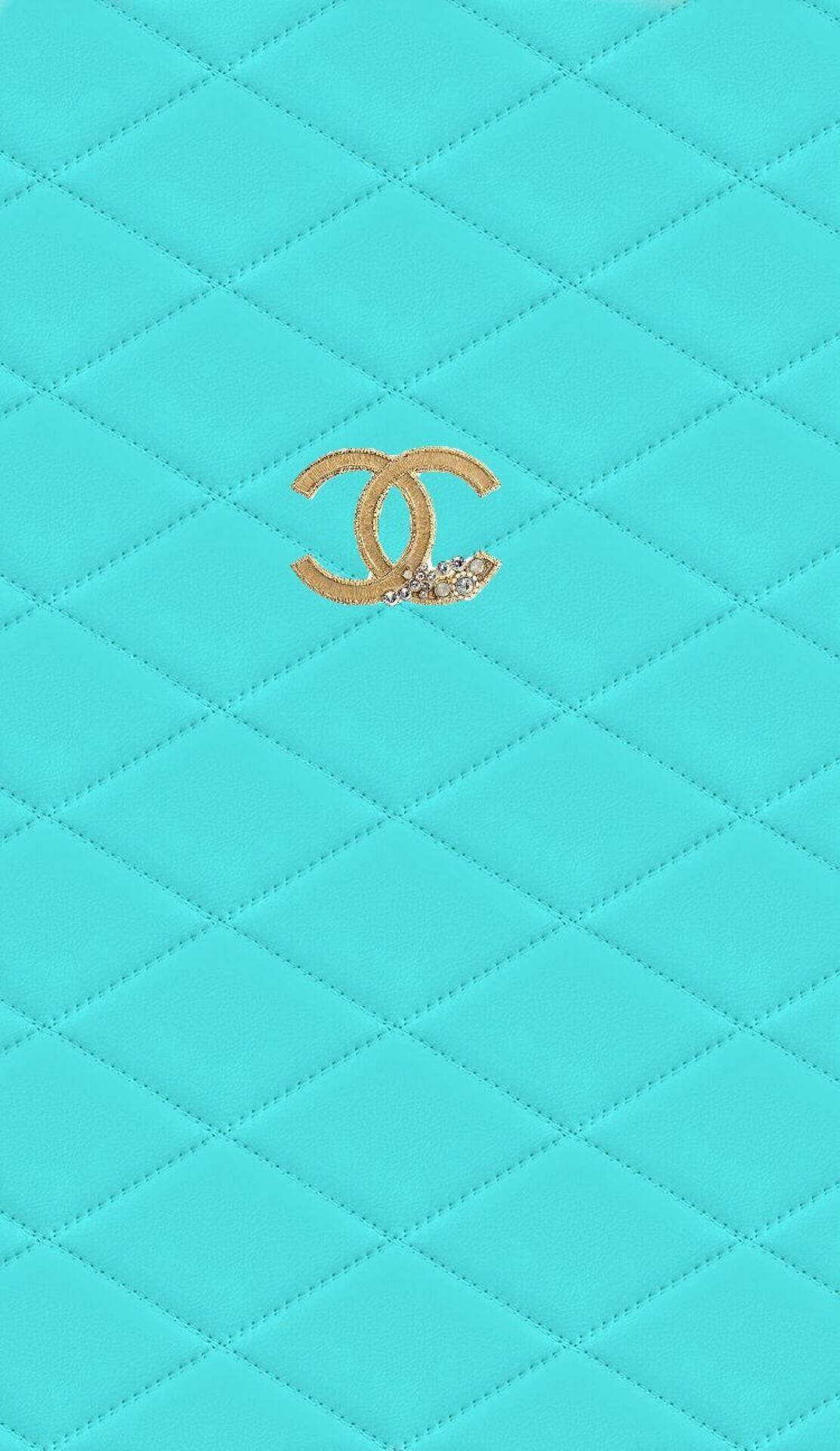 tiffany 桌布 壁紙 — 藍綠色絎縫皮革表面，金色Chanel標誌帶有閃爍裝飾，居中於框架內。