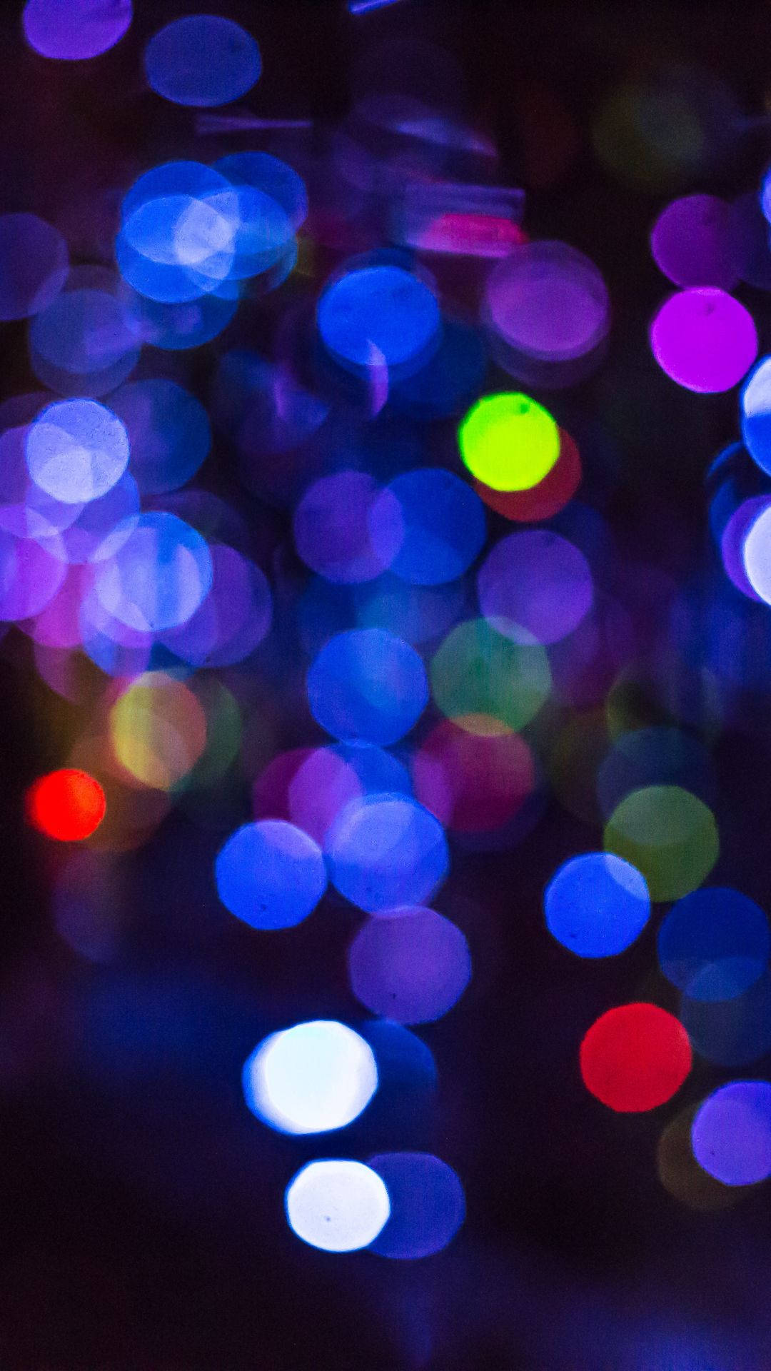 Bokeh 桌布 壁紙 — 藍色、紫色和綠色的鮮豔散景燈光在黑暗背景上柔和地發光。