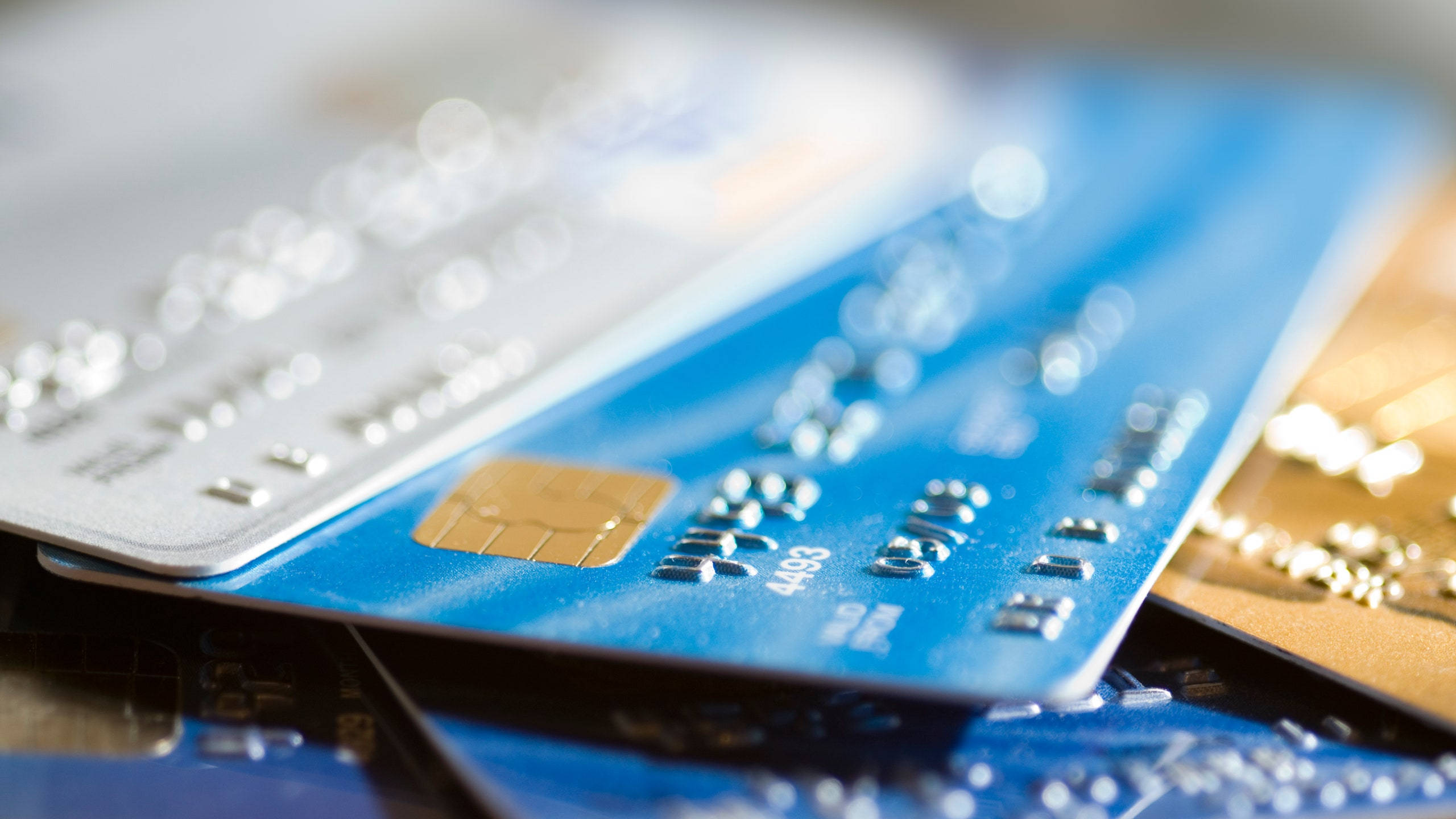 Credit Card 桌布 壁紙 — 藍色、銀色和金色信用卡疊放的近距離特寫，背景模糊，景深較淺。