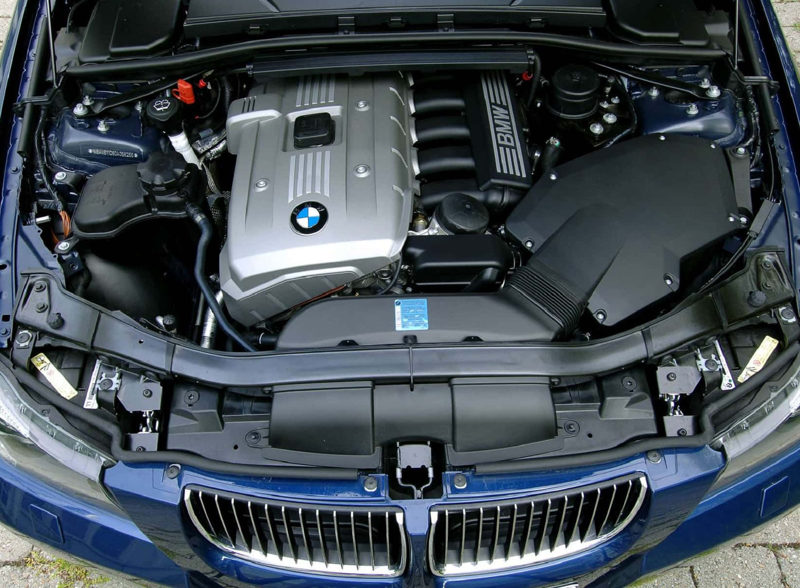 引擎 桌布 壁紙 — 藍色BMW汽車打開引擎蓋的近距離視圖，顯示其詳細的銀色引擎室，帶有可見的組件和品牌標誌。