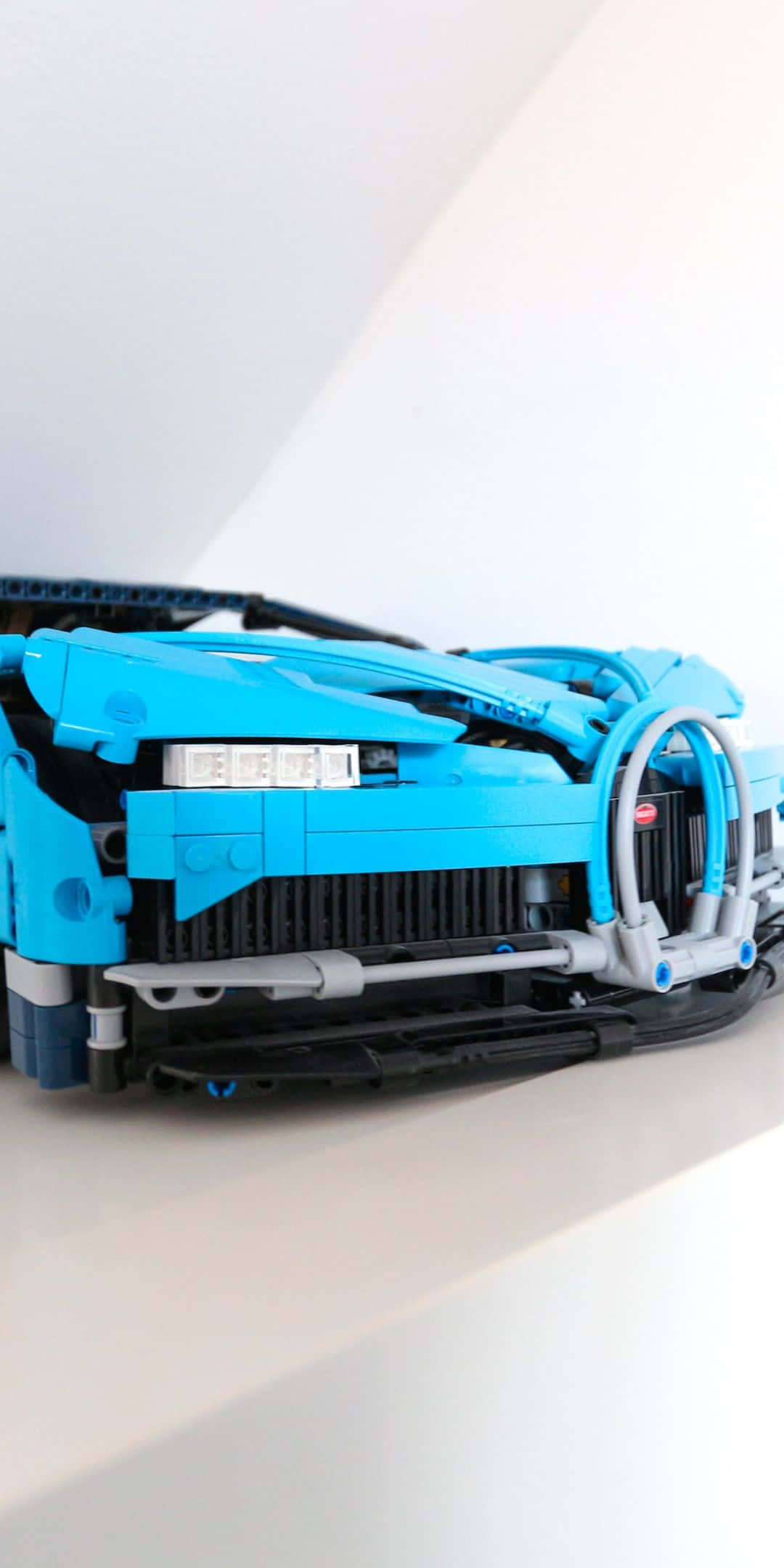 樂高 桌布 壁紙 — 藍色LEGO Technic跑車模型的近距離特寫，在簡約白色背景上展示複雜的機械細節。