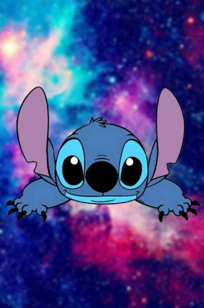 kawaii stitch 桌布 壁紙 — 藍色卡通外星人史迪奇在紫色、粉紅色和藍色的鮮豔宇宙星雲背景下快樂地漂浮。