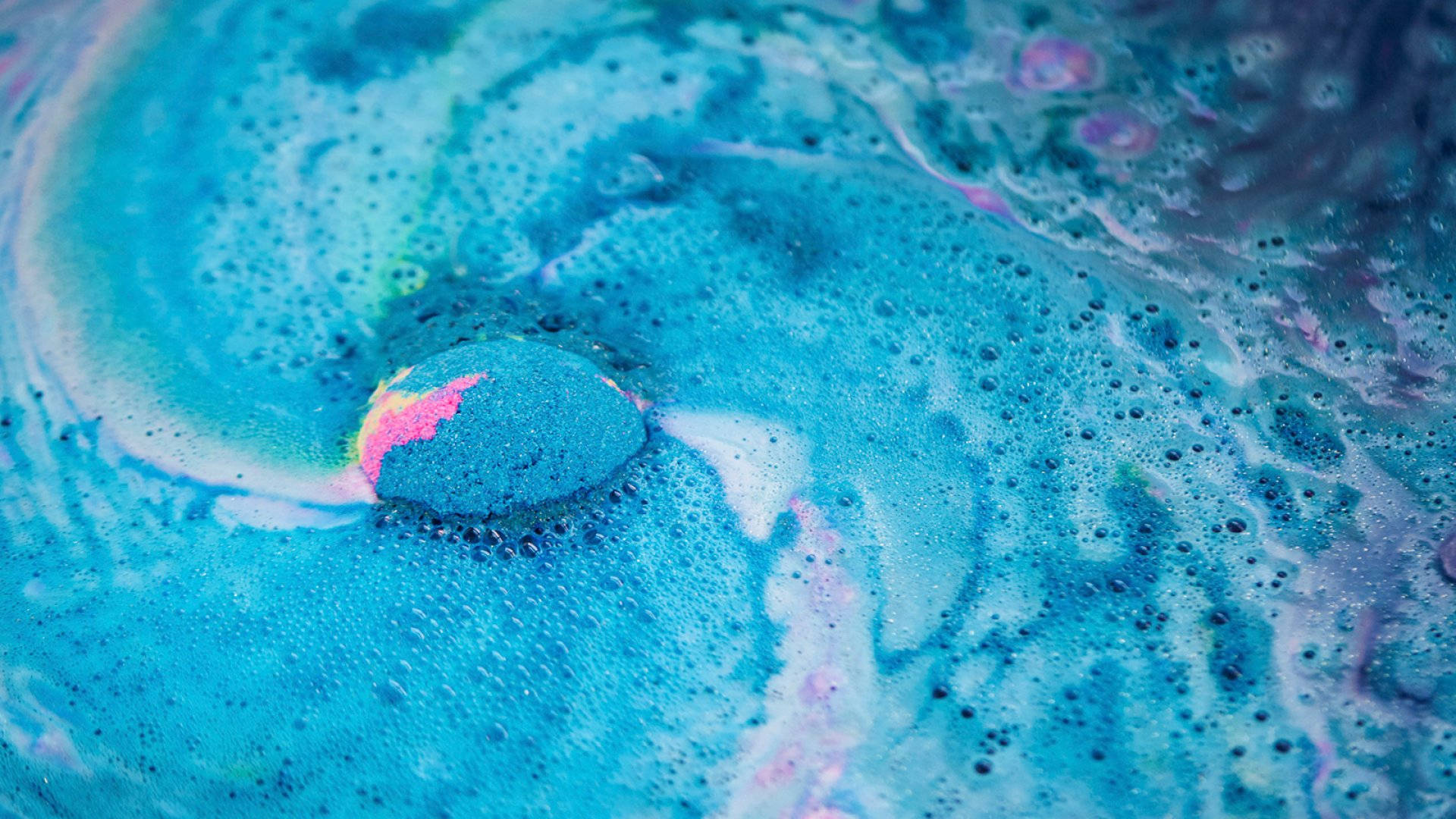 Lush 桌布 壁紙 — 藍色和粉紅色漩渦氣泡液體的近距離特寫，中央氣泡爆裂成彩虹色泡沫。
