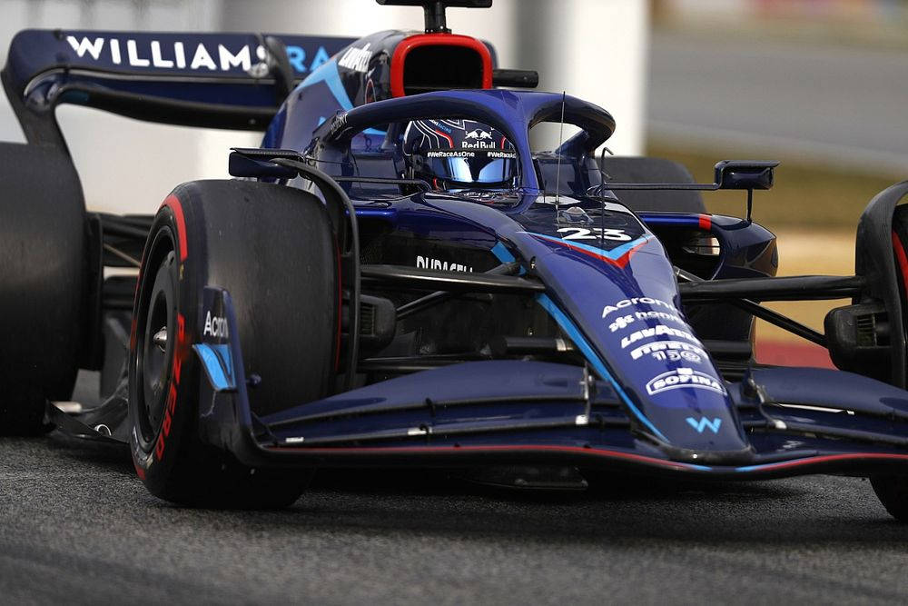 F1 桌布 壁紙 — 藍色和紅色威廉姆斯一級方程式賽車在賽道上飛馳的特寫，可見贊助商標誌和車手頭盔。