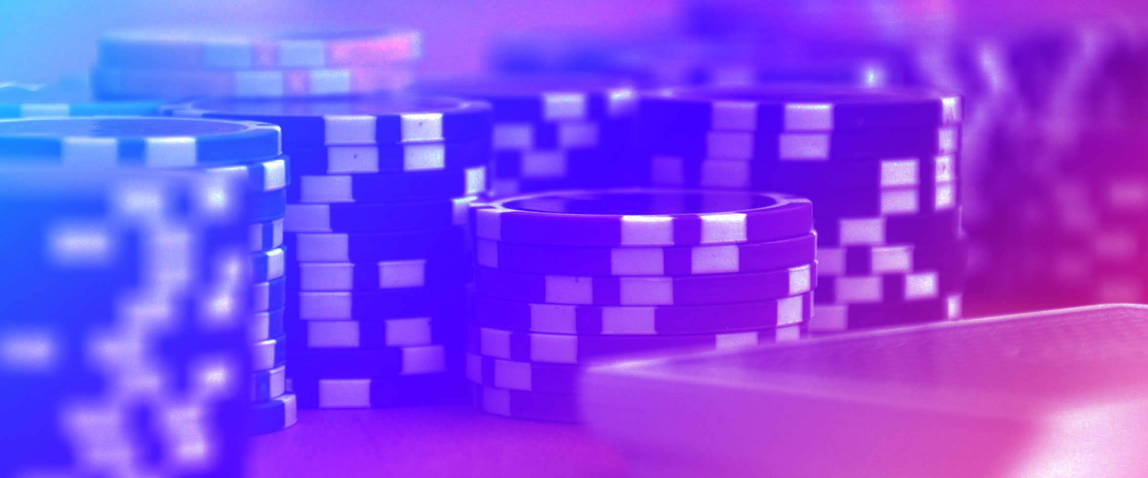 chips 桌布 壁紙 — 藍色和紫色的籌碼堆在遊戲桌上鮮豔的霓虹燈光下閃耀。