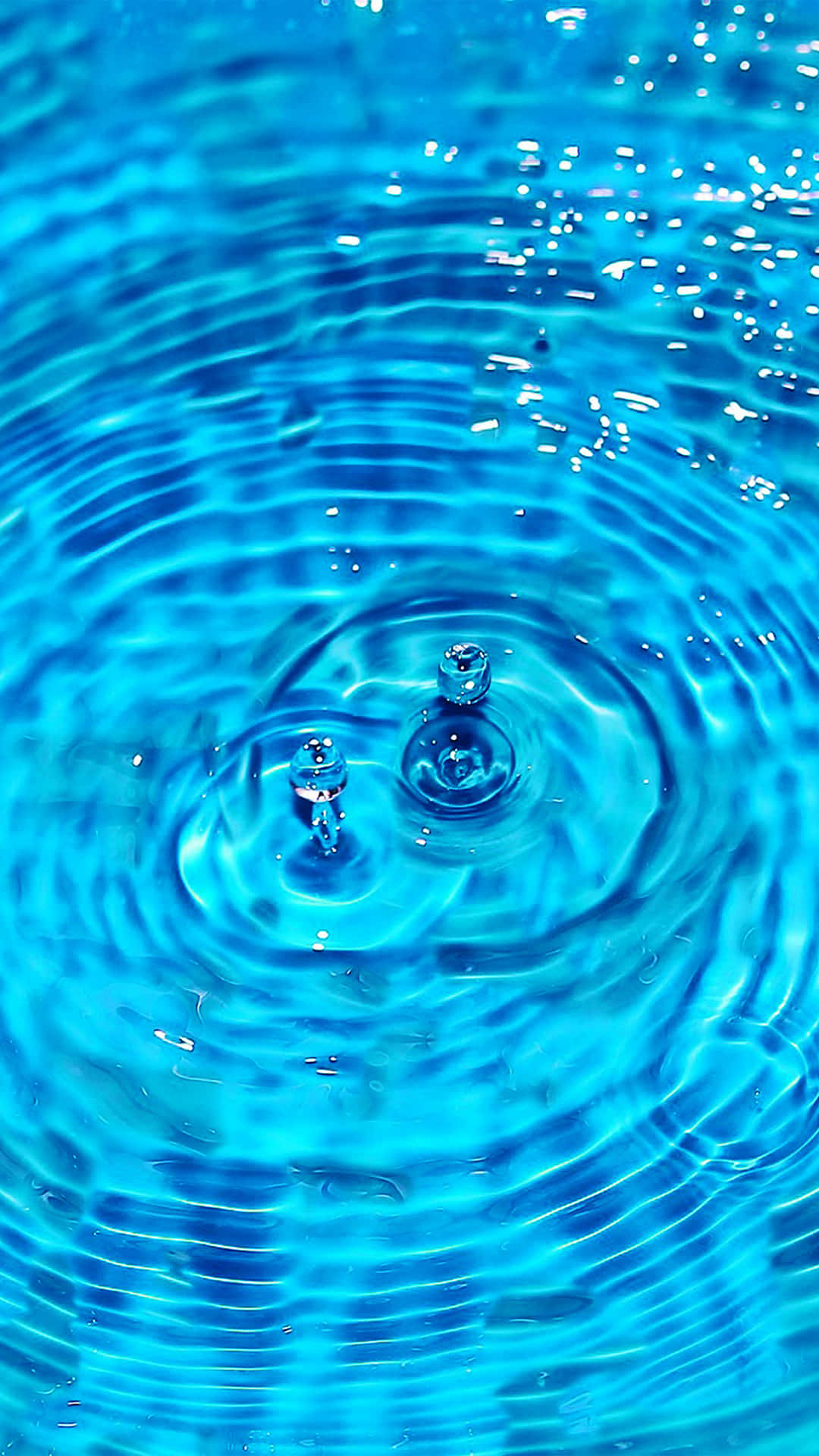 Water 桌布 壁紙 — 藍色水波紋從中央飛濺處向外擴散的特寫，帶有閃爍的水滴。