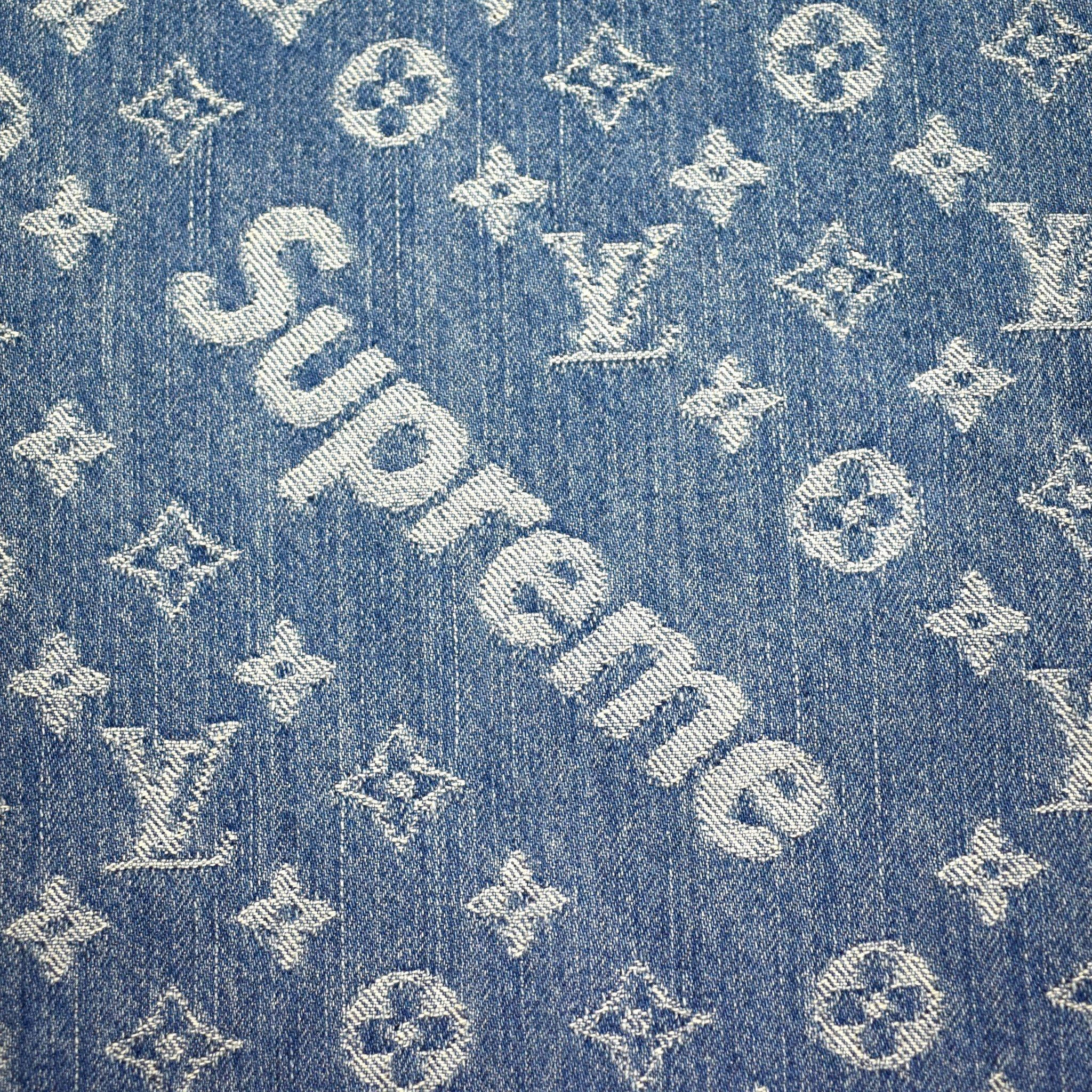 Denim 桌布 壁紙 — 藍色牛仔布料的特寫，帶有白色刺繡的 Louis Vuitton 字母組合和斜向的 Supreme 標誌。