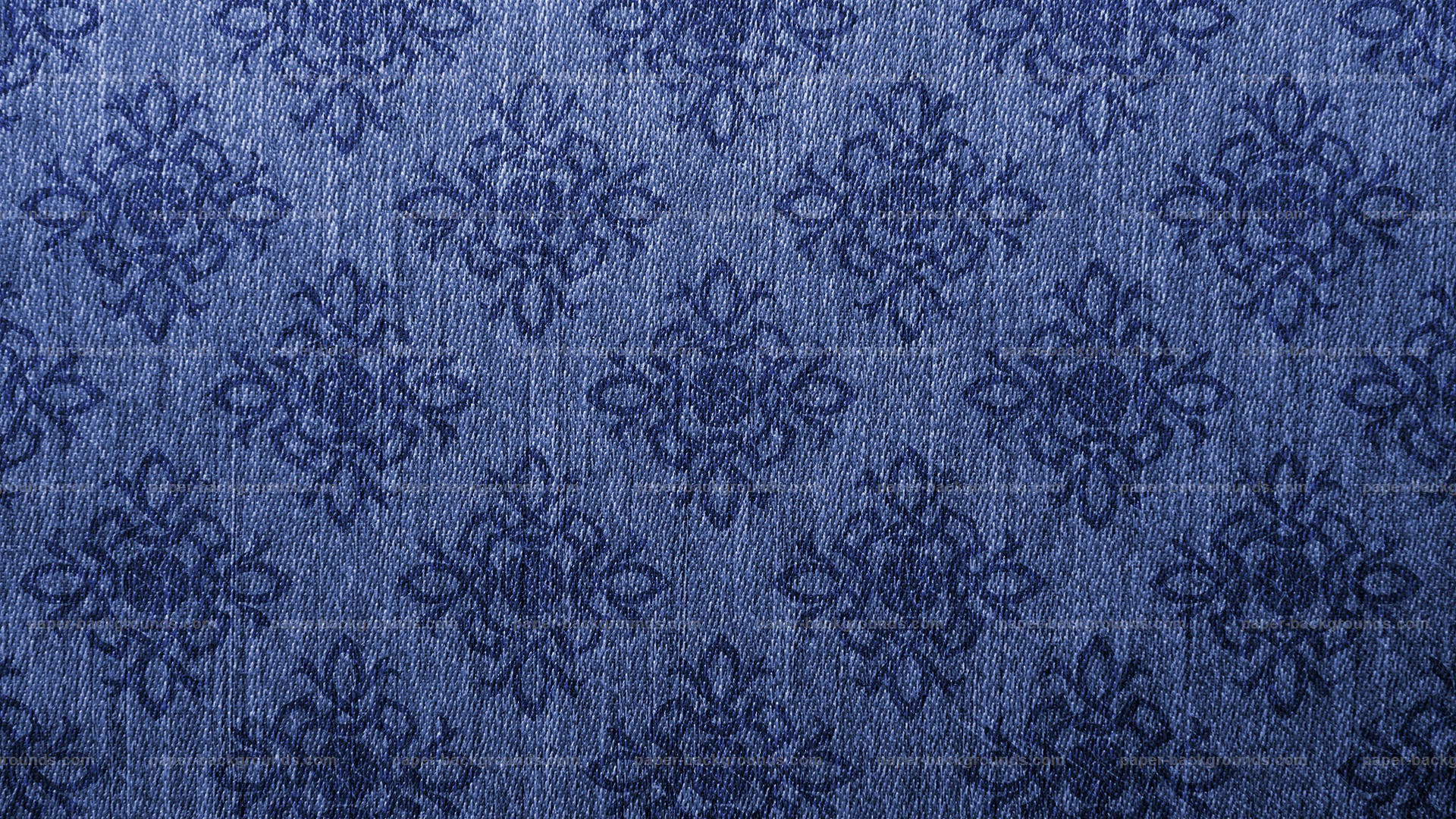 Blue Texture 桌布 壁紙 — 藍色牛仔布料的特寫，帶有重複的深色花卉刺繡圖案。