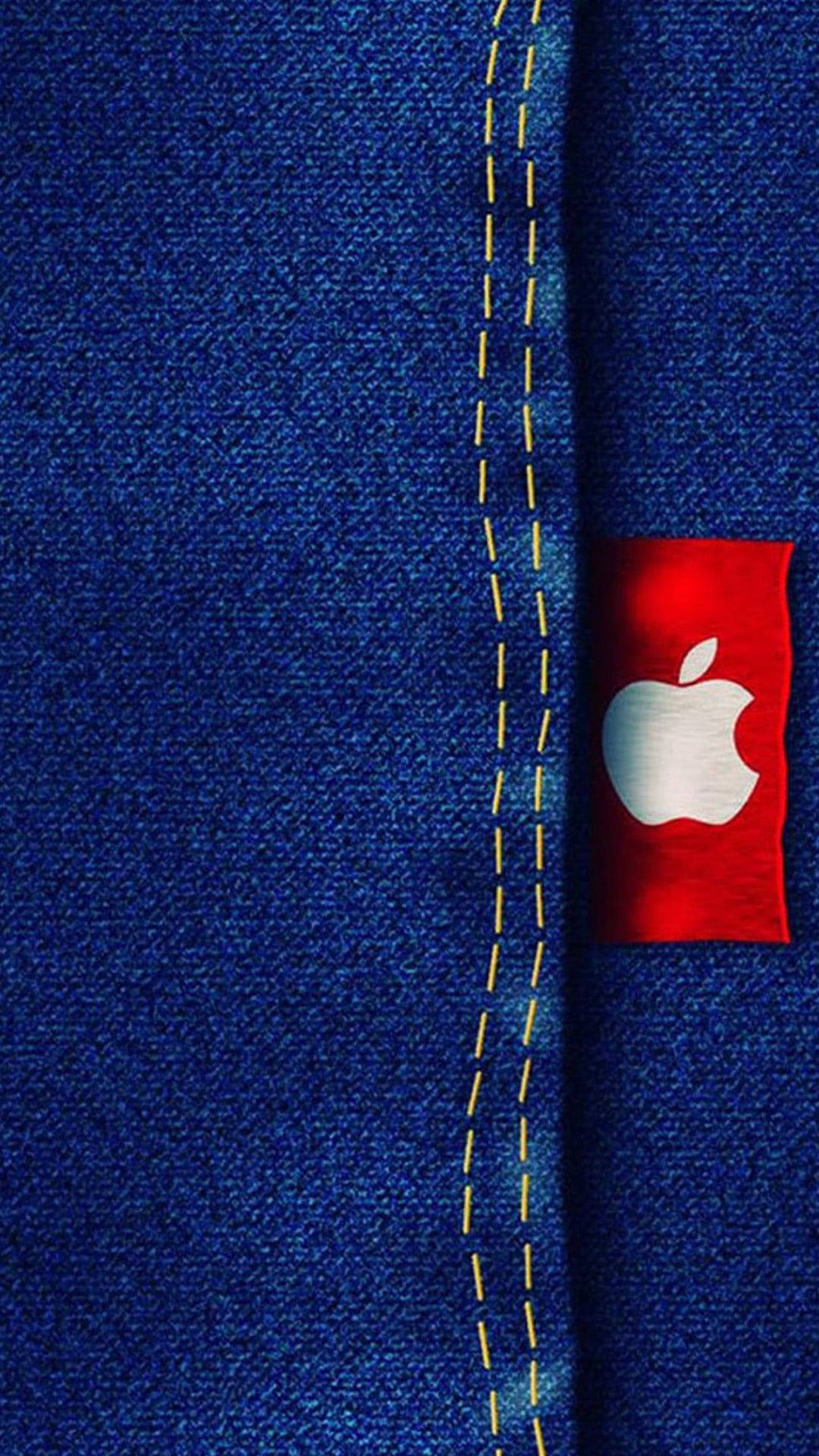 Denim 桌布 壁紙 — 藍色牛仔布料的特寫，帶有黃色縫線和一個帶有白色Apple標誌的紅色補丁。