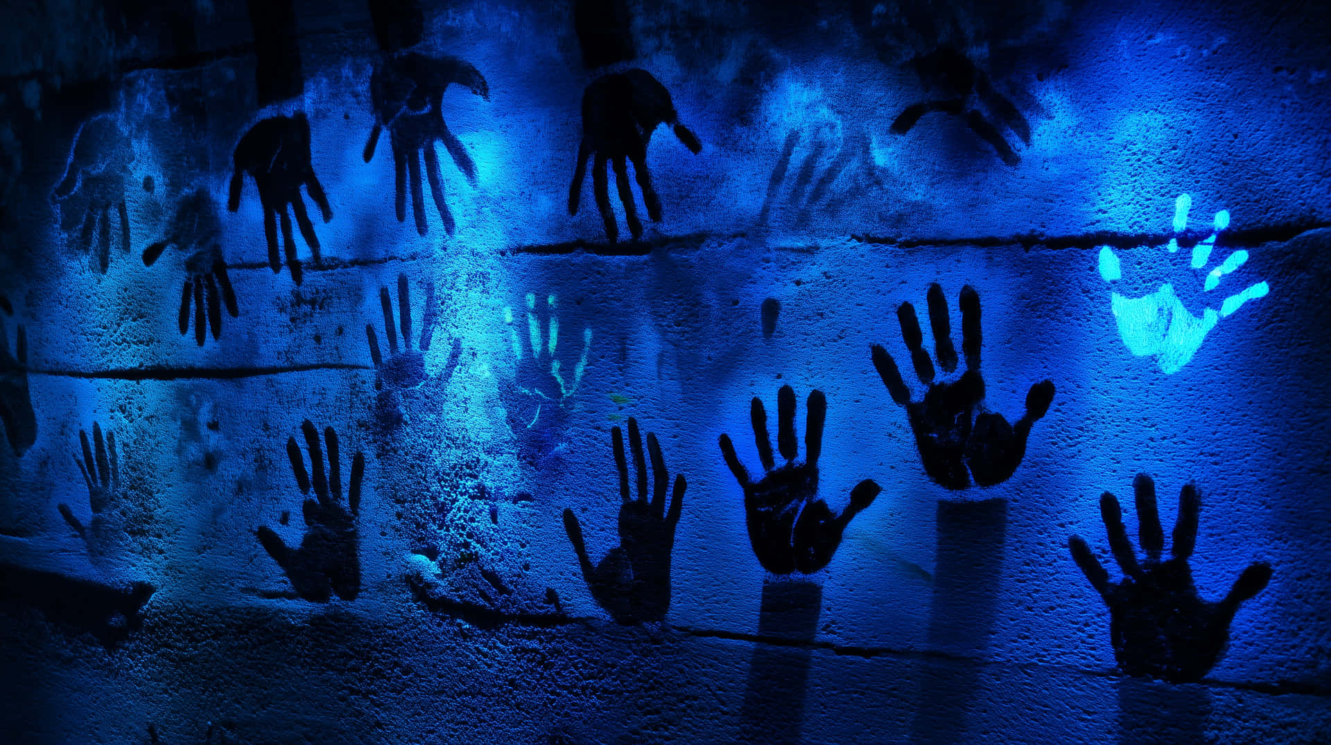 Bold Blue Handprint Among Shadowed Impressions 壁紙 — 藍色發光的手印壓在粗糙的紋理牆上，營造出令人難忘的藝術展示。