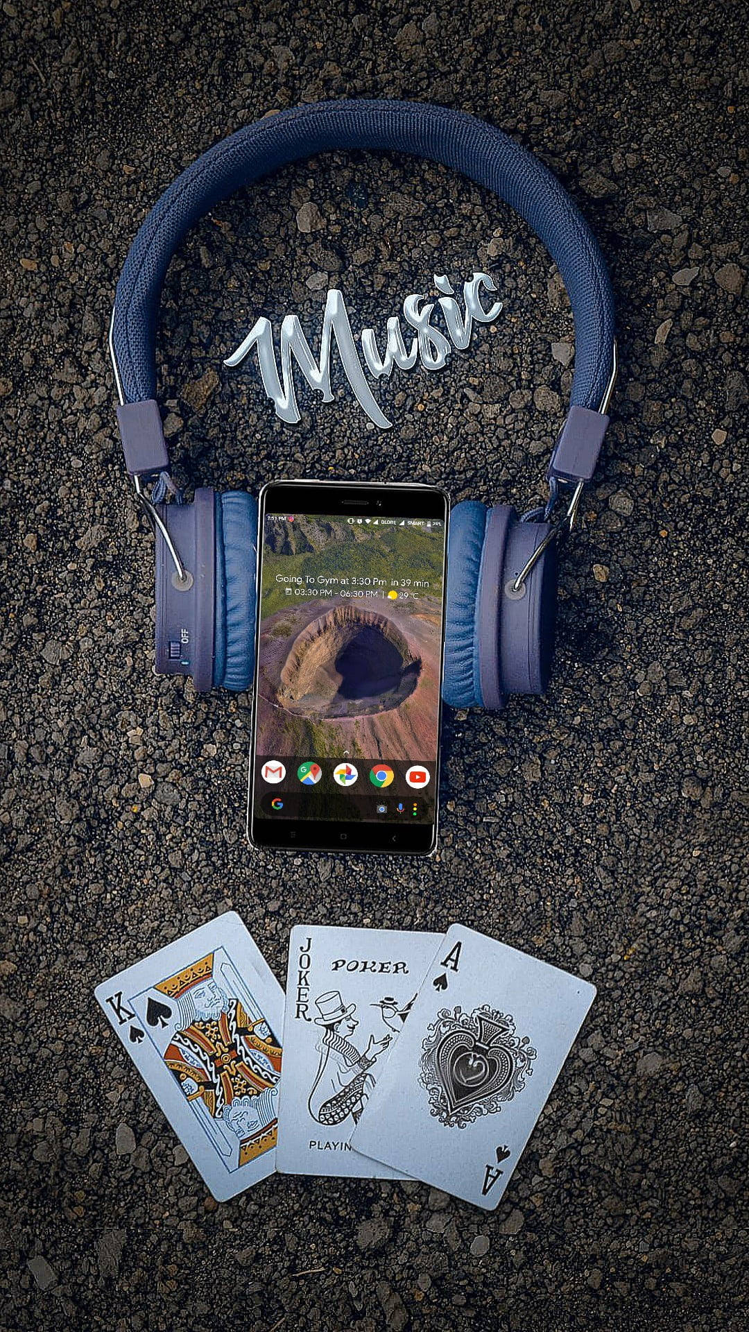 listening to music 桌布 壁紙 — 藍色耳機框住一部智慧型手機，顯示峽谷場景，上方有「Music」字樣，下方碎石上散落著撲克牌。