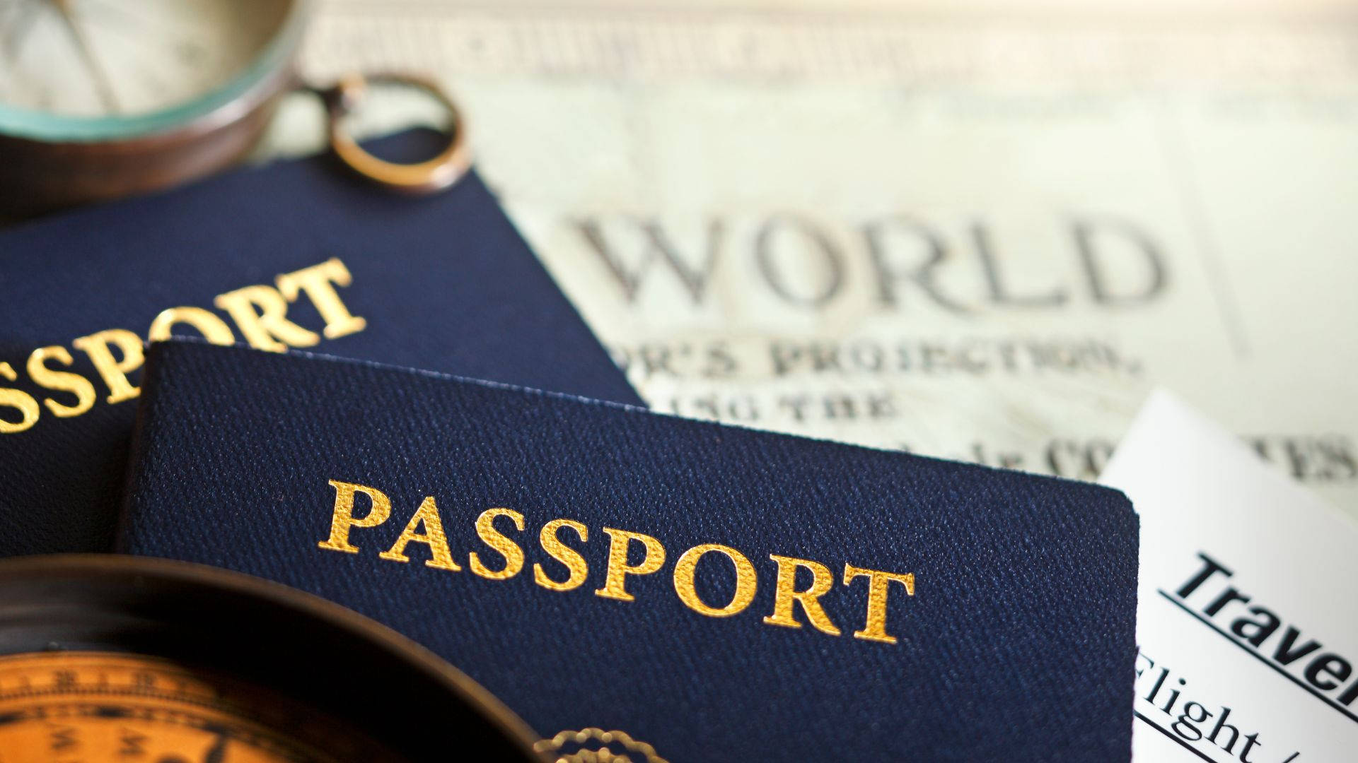 Passport 桌布 壁紙 — 藍色護照特寫，金色字體，放在世界地圖和旅行文件上。