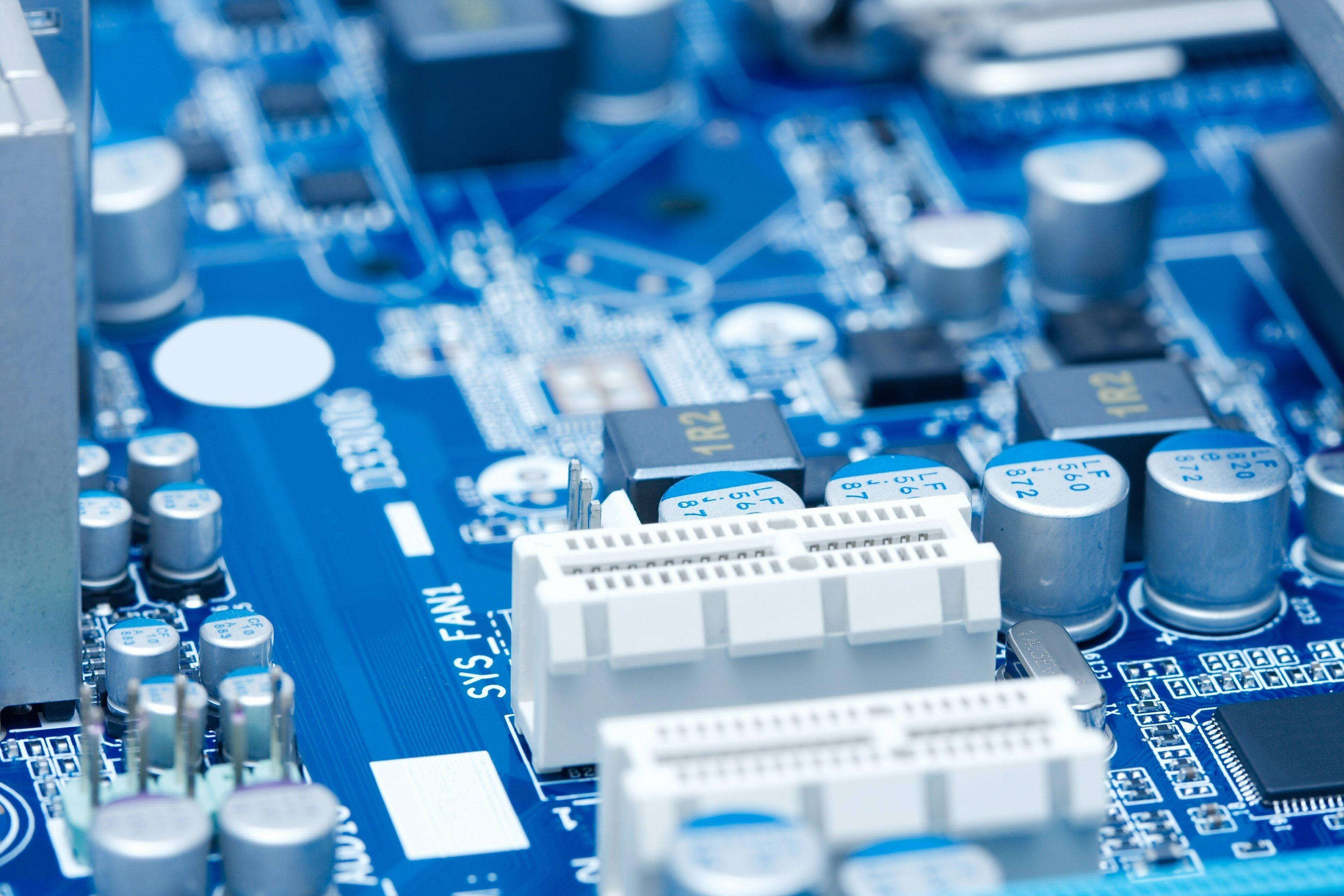 Motherboard 桌布 壁紙 — 藍色電腦主機板特寫，銀色電容和白色連接器，焦點清晰。