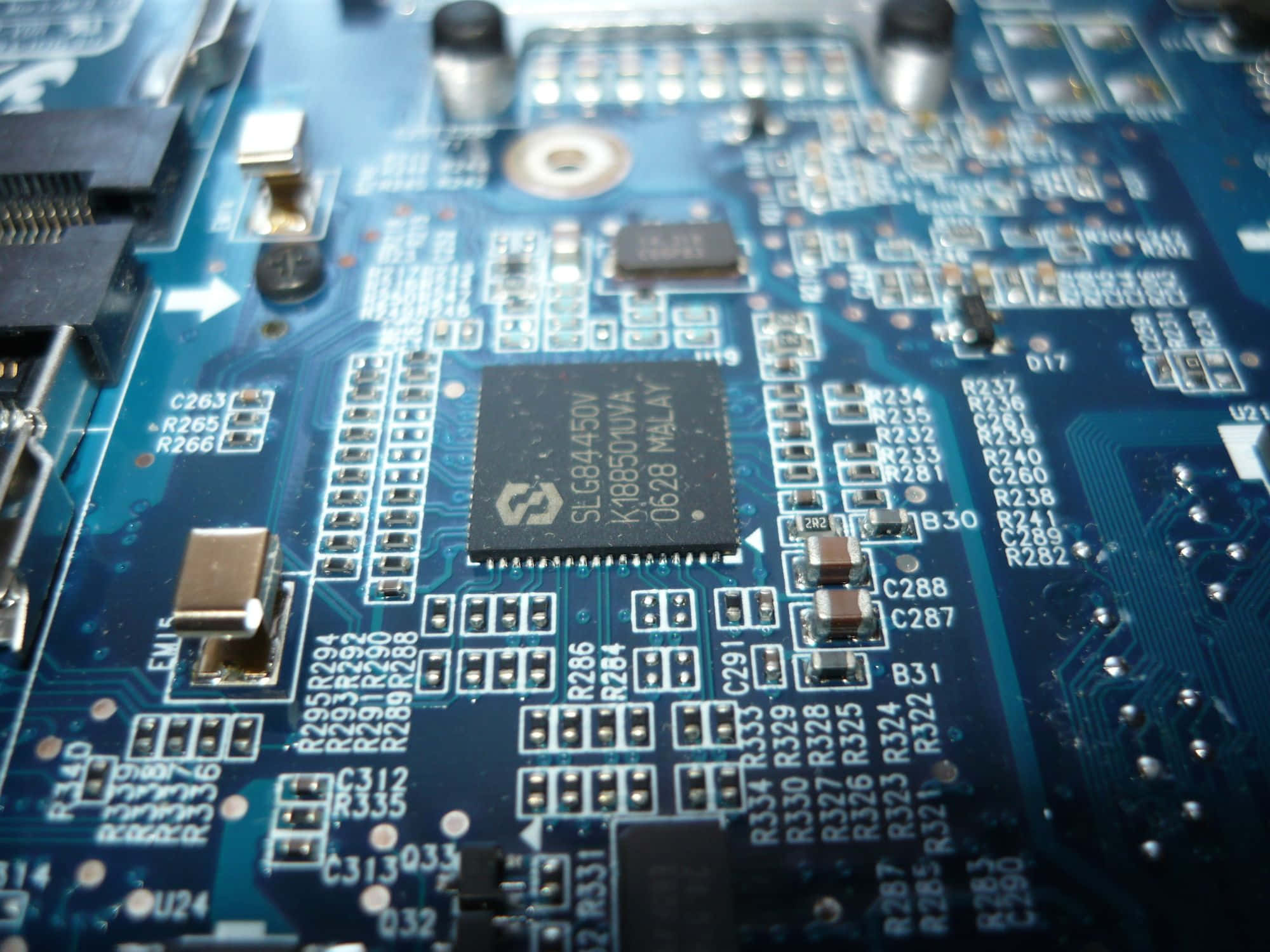 Electronics 桌布 壁紙 — 藍色電路板的特寫，上面有複雜的線路和標籤的電子元件，在明亮的燈光下。