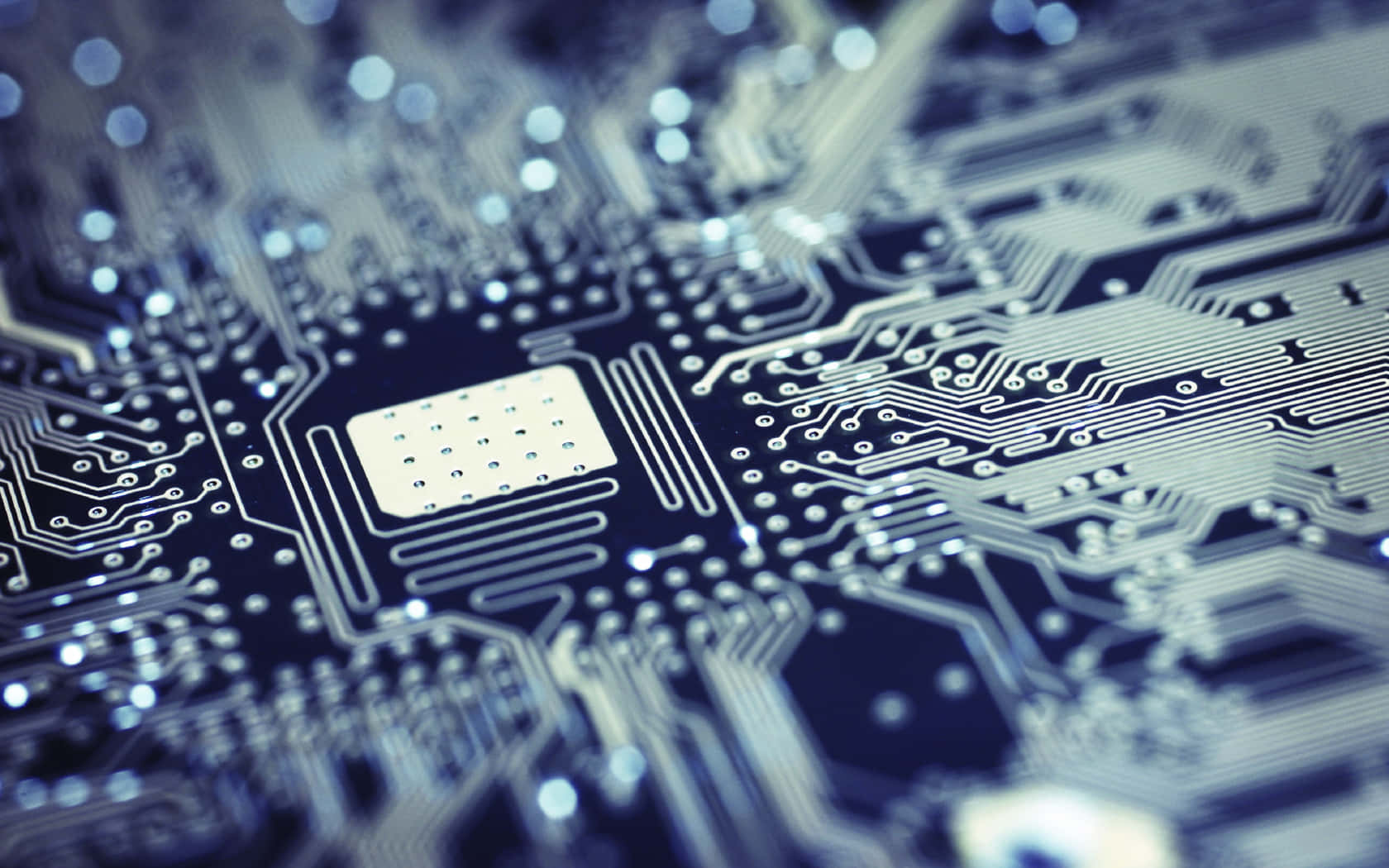 Electronics 桌布 壁紙 — 藍色電路板的特寫，帶有複雜的銀色路徑和一個中央晶片，在淺景深下柔和發光。