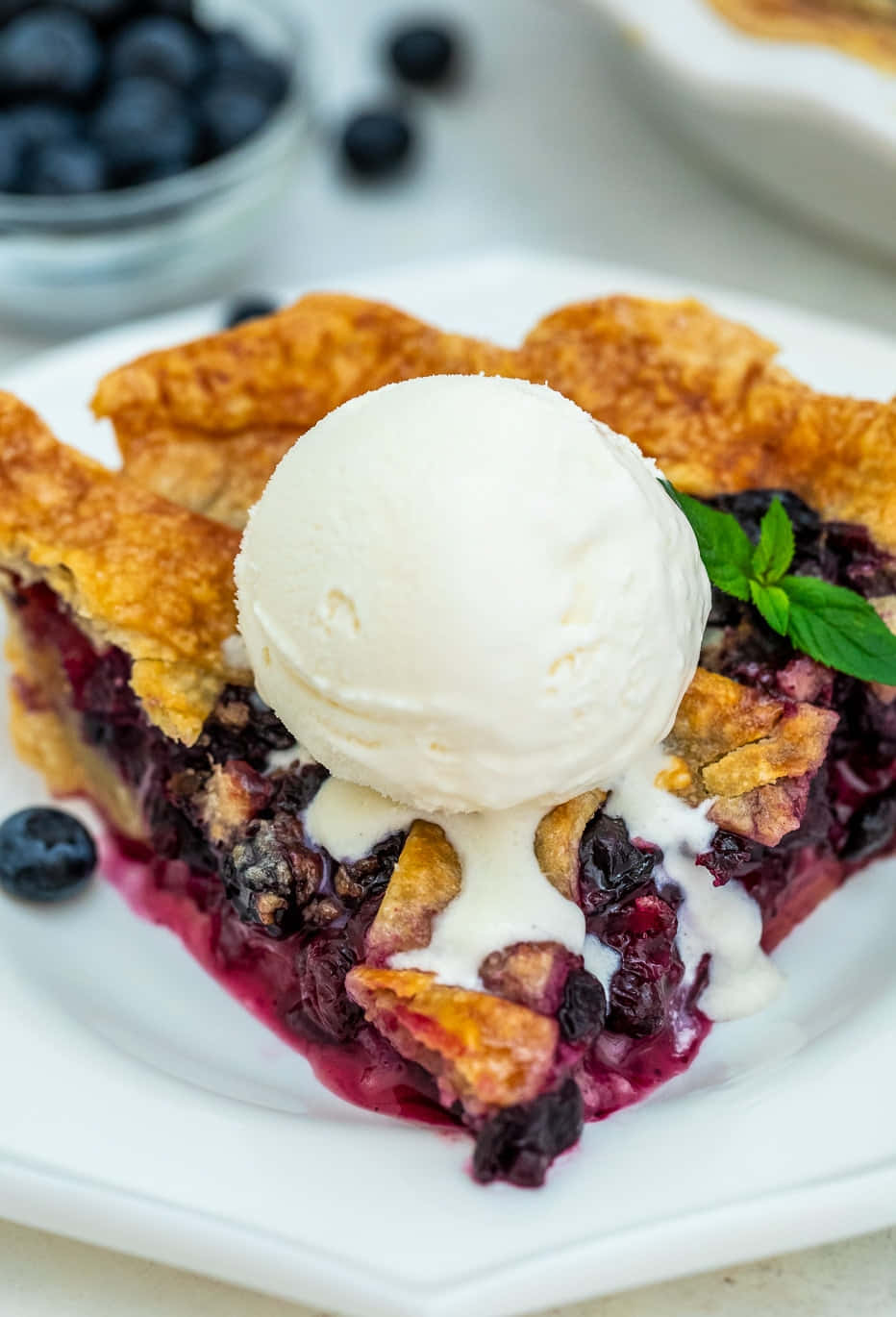 Blueberry Pie 桌布 壁紙 — 藍莓派一片的特寫，金黃色的派皮上配有融化的香草冰淇淋和新鮮薄荷。