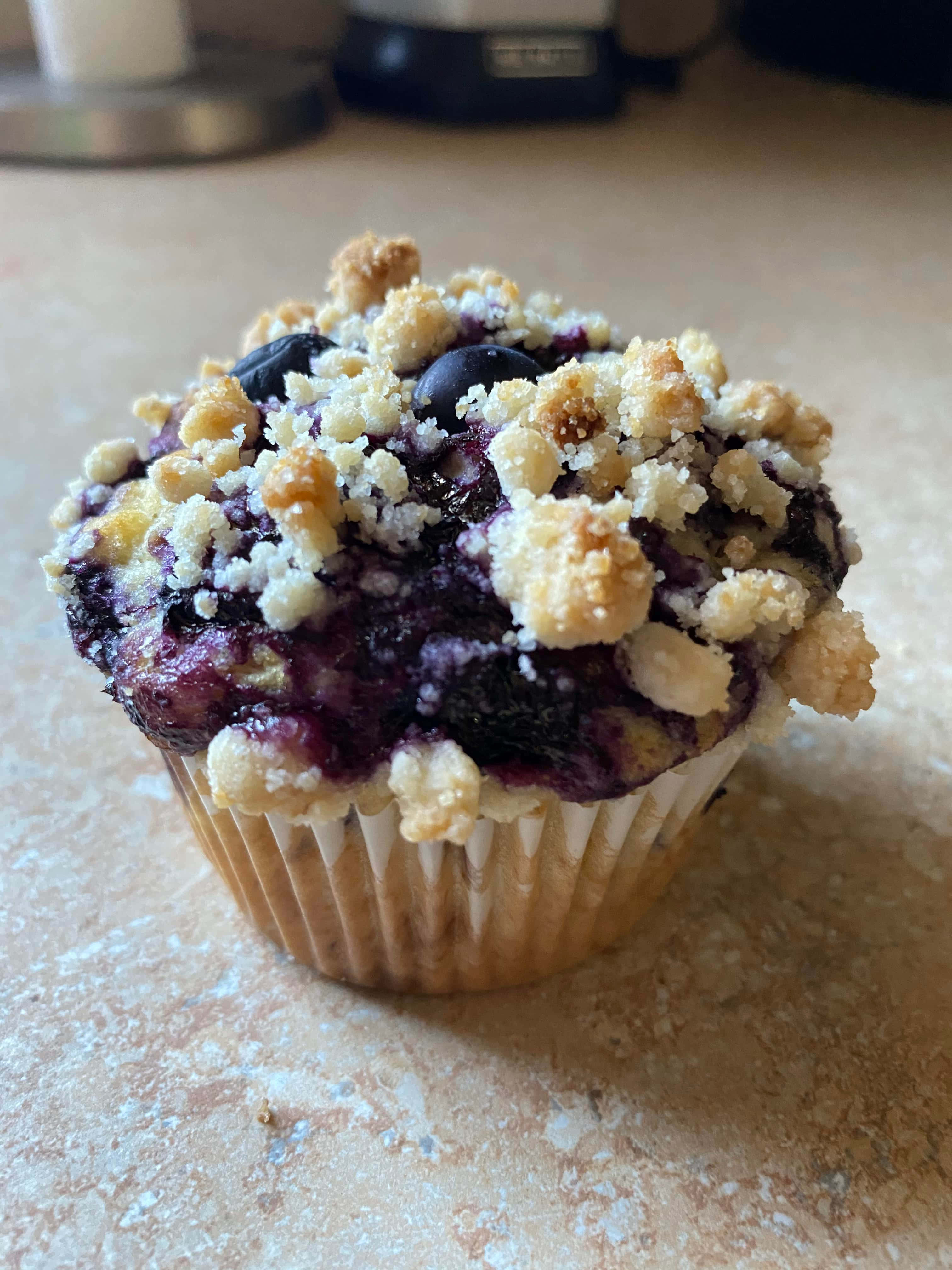 Blueberry Muffins 桌布 壁紙 — 藍莓馬芬特寫，金黃酥粒頂層，置於灑滿麵粉的檯面上。