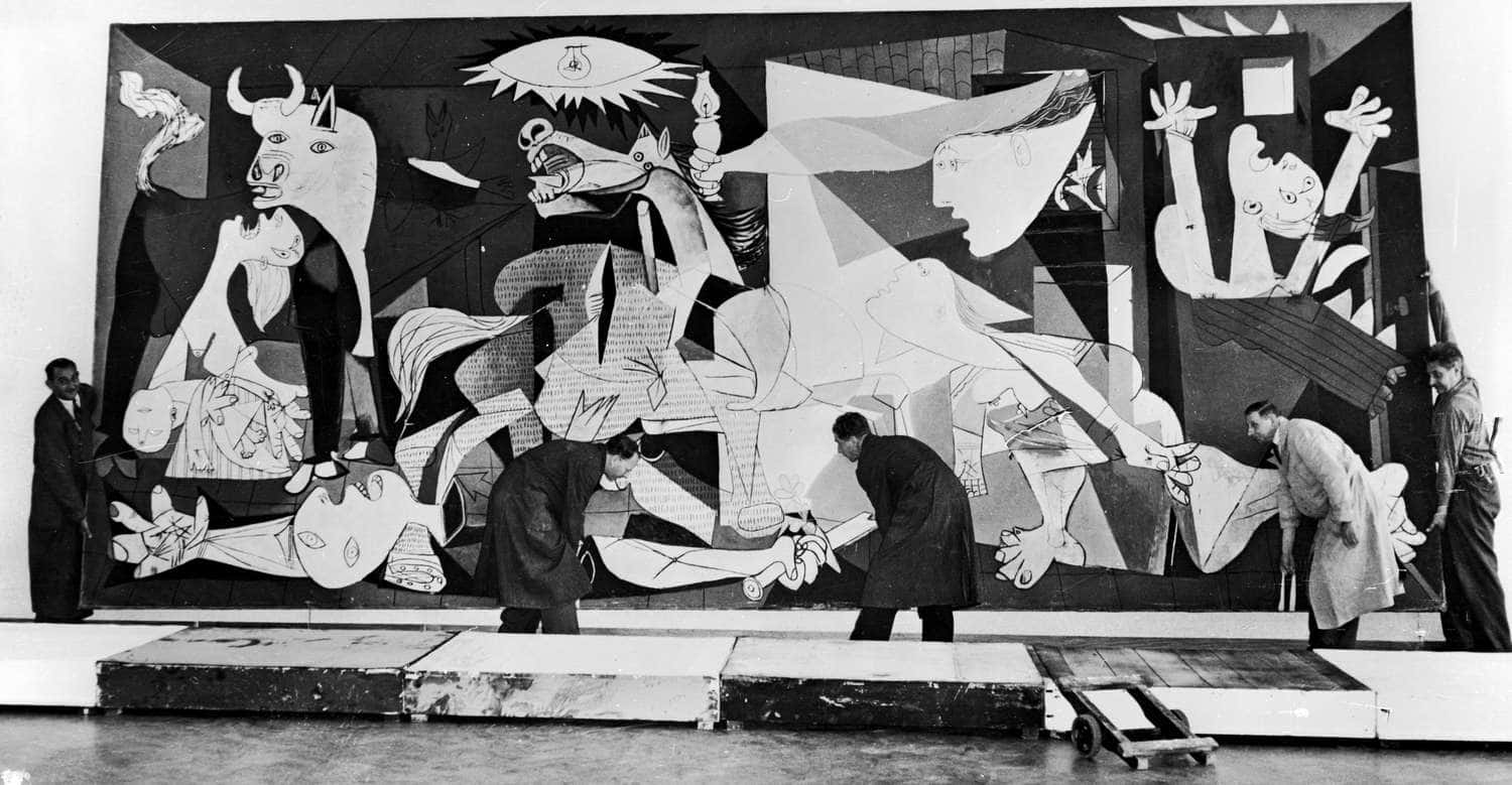 Picasso 桌布 壁紙 — 藝術家在畫廊空間安裝一幅巨大的黑白立體派壁畫，描繪扭曲的公牛和鬥牛士形象。
