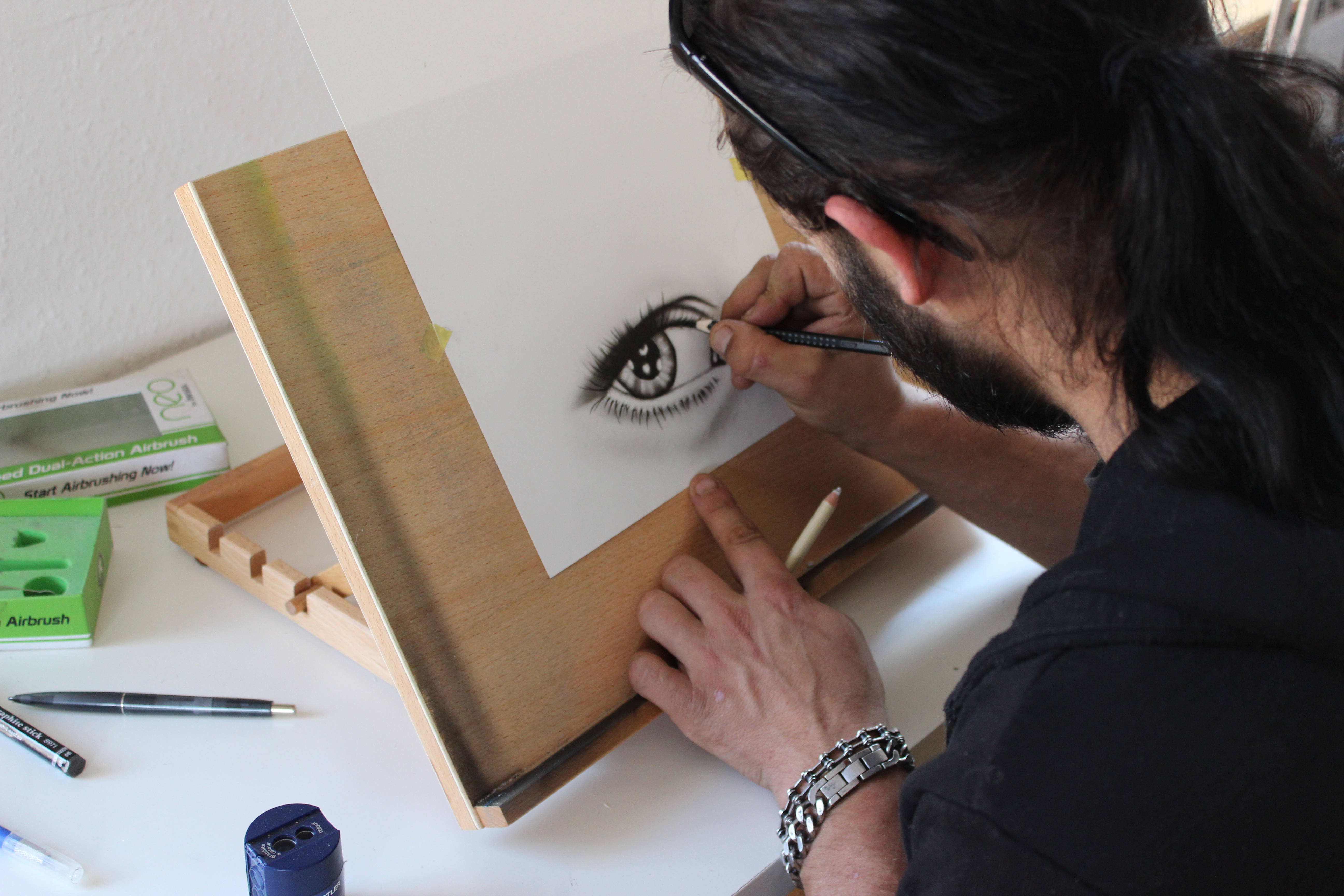 pencil 桌布 壁紙 — 藝術家用細筆在木畫架上仔細地素描紙上的人眼細節。