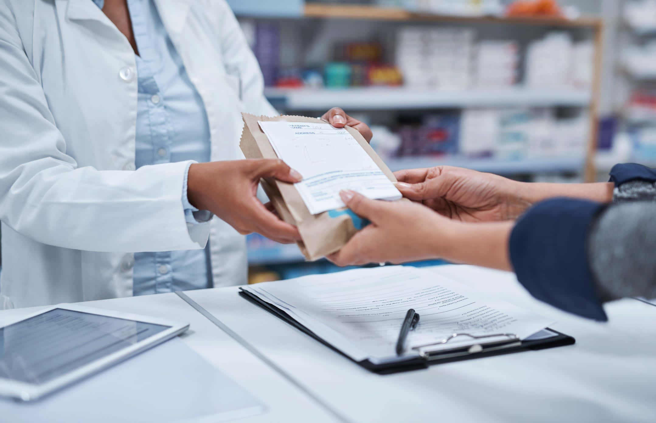 Customer Service 桌布 壁紙 — 藥劑師在藥局櫃檯將一個裝有藥物的棕色紙袋遞給顧客。