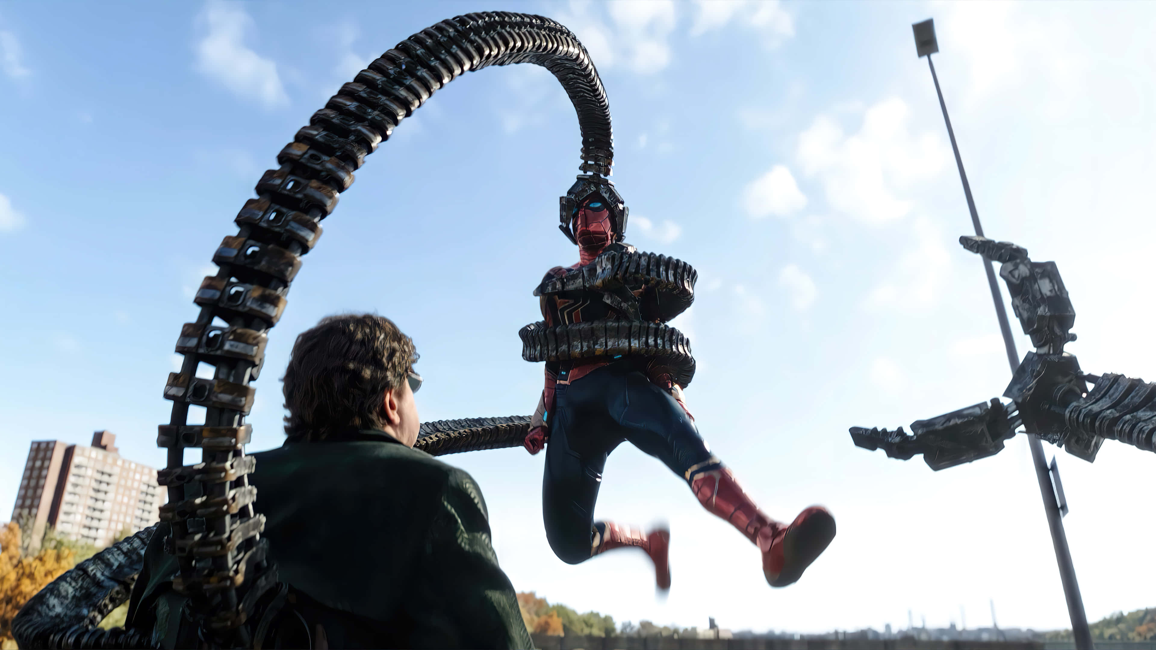 Spider Man No Way Home 桌布 壁紙 — 蜘蛛人在城市景觀中擺盪，躲避機械觸手，同時一名男子從下方觀看。