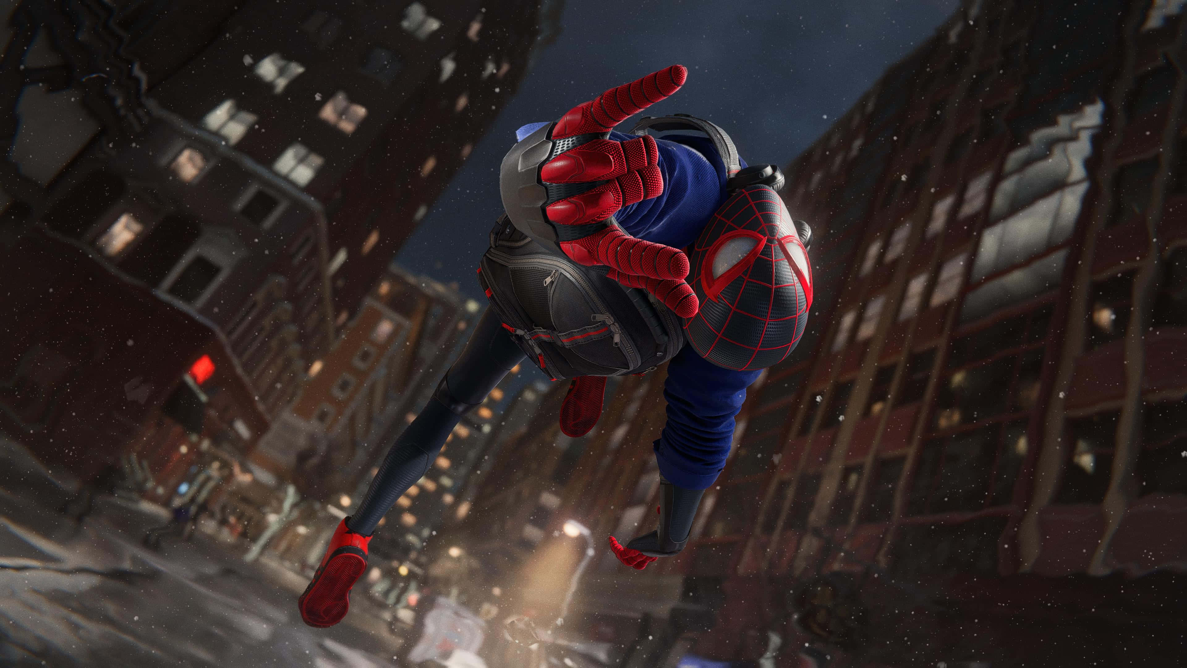 Web-slinging 桌布 壁紙 — 蜘蛛人在夜晚穿越白雪覆蓋的城市景觀，下方是高聳的建築物，周圍飄落著雪花。