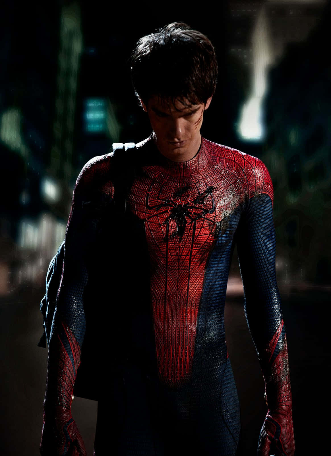 Andrew Garfield Spider Man 桌布 壁紙 — 蜘蛛人夜晚站在被雨水浸濕的城市街道上，他的紅藍戰衣在昏暗的路燈下閃閃發光。