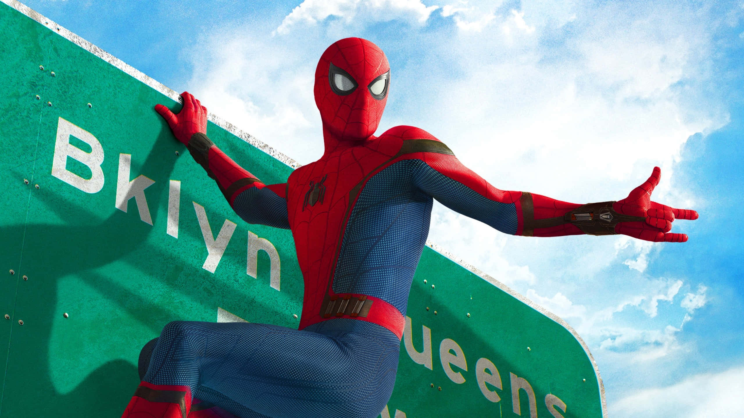 Ultimate Spider-man 桌布 壁紙 — 蜘蛛人穿著紅藍戰衣，蹲在綠色布魯克林皇后區高速公路標誌上，背景是晴朗藍天和 fluffy 雲朵。