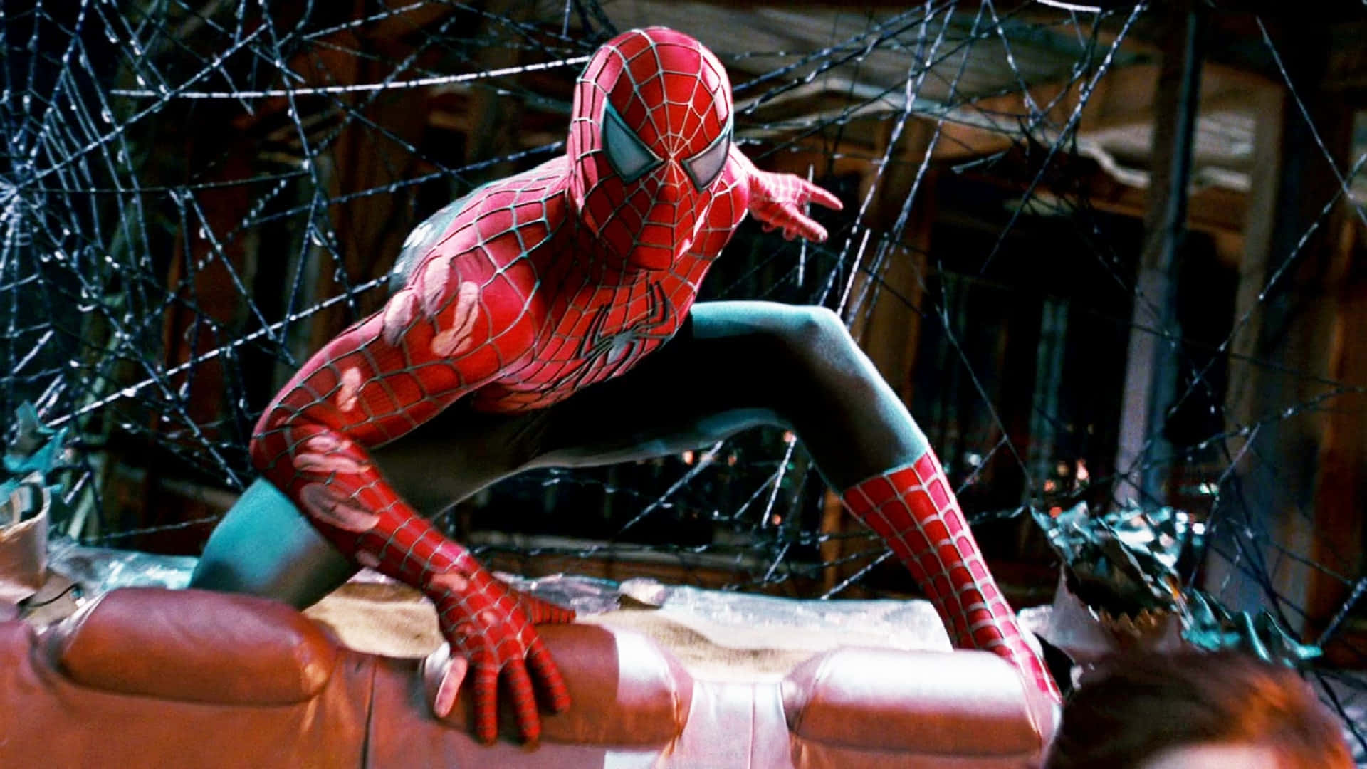 Spider Man 3 桌布 壁紙 — 蜘蛛人蹲在破爛的皮沙發上，周圍是碎玻璃，房間光線昏暗。