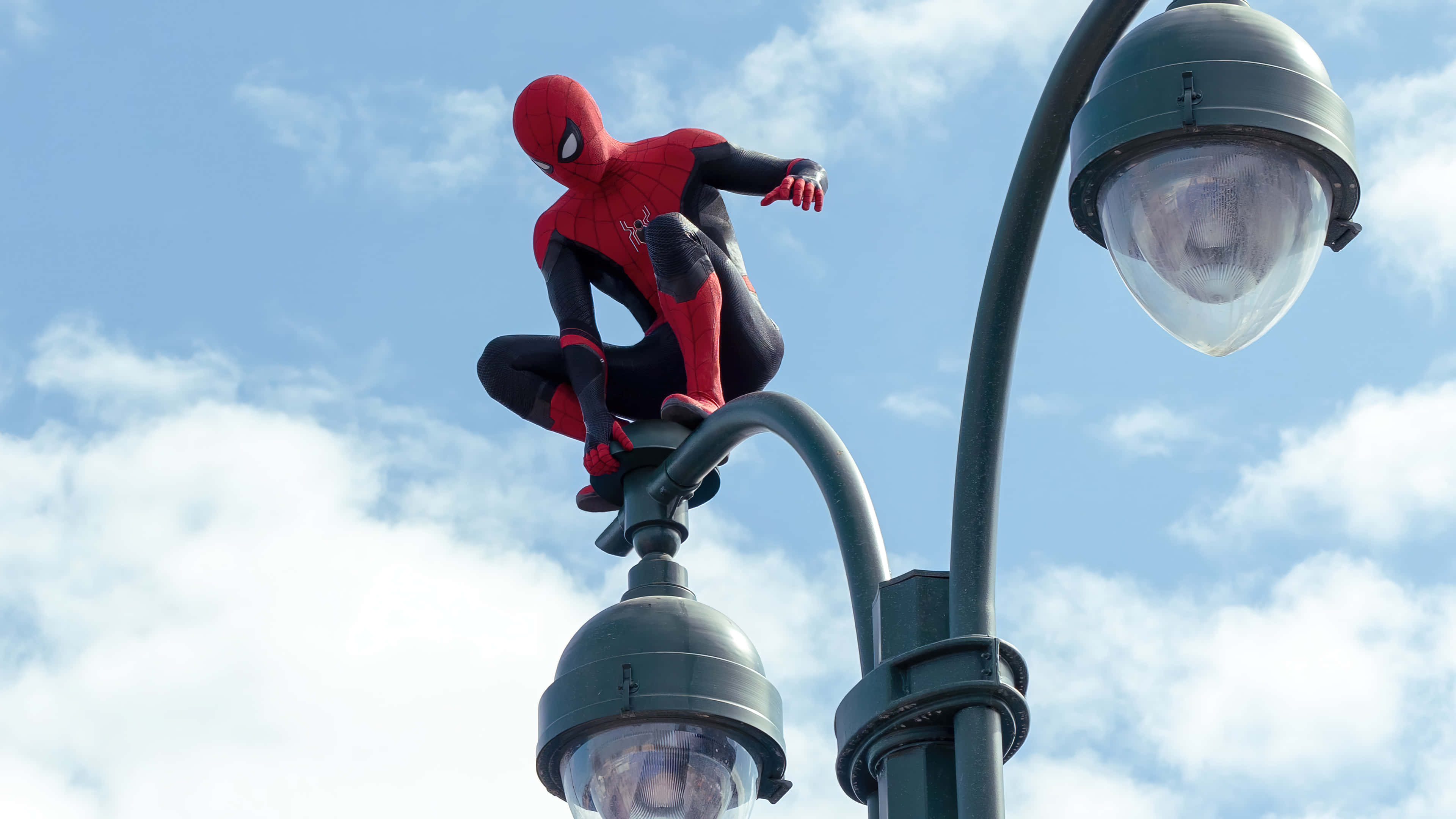 Spider Man No Way Home 桌布 壁紙 — 蜘蛛人蹲在街燈頂上，背景是明亮的藍天和蓬鬆的白雲。